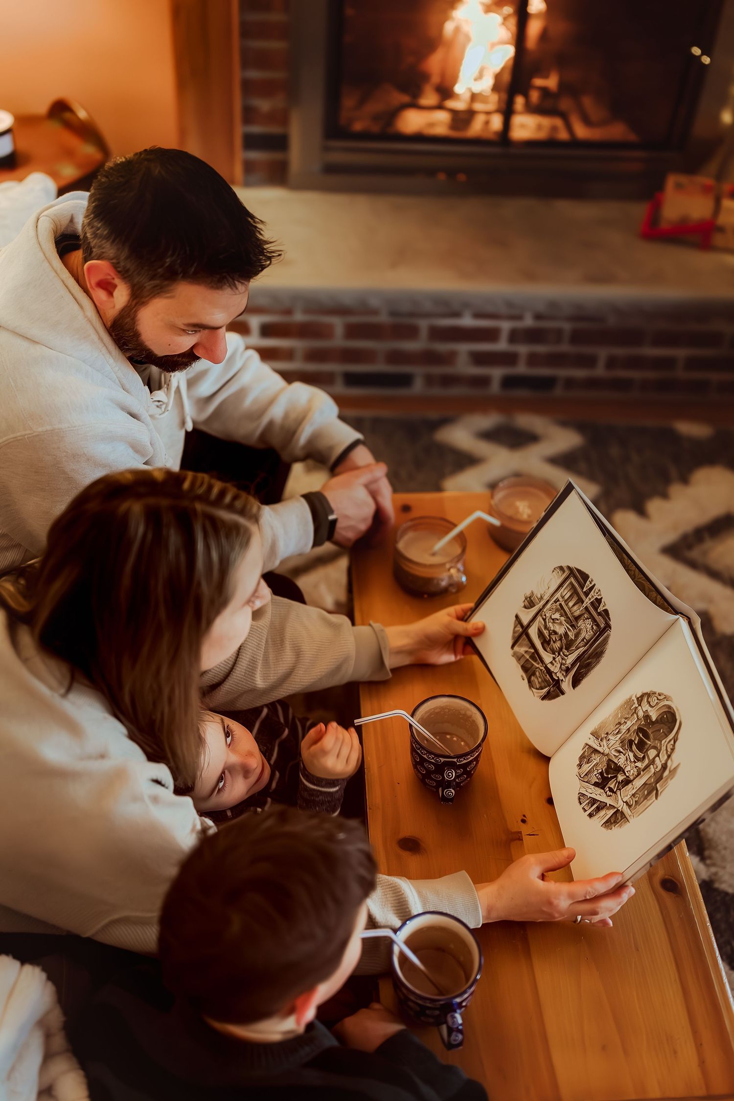 Two people lean over a wooden table examining artwork together in warm lighting.