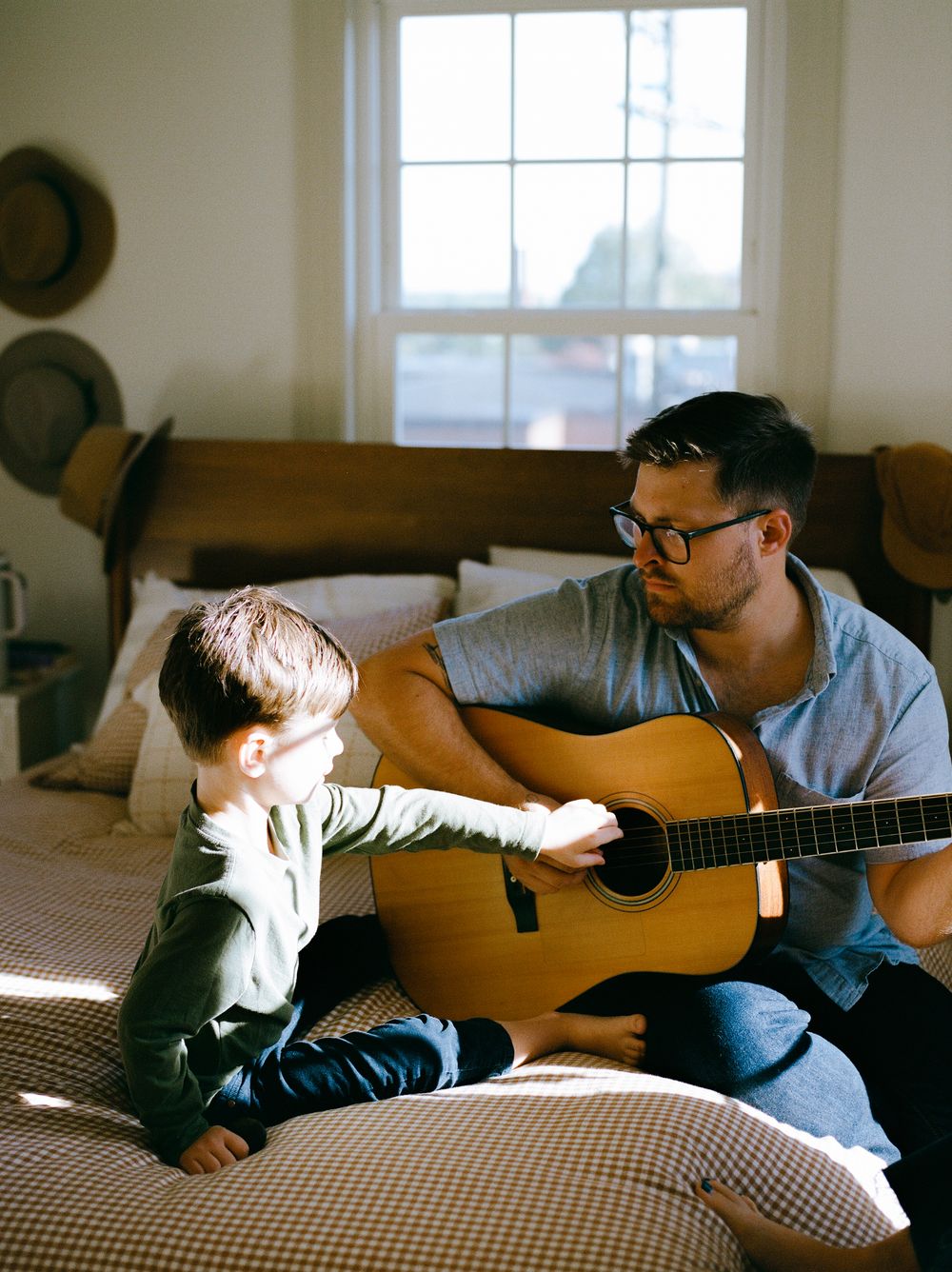 Person playing acoustic guitar while relaxing on a couch in a sunny room.