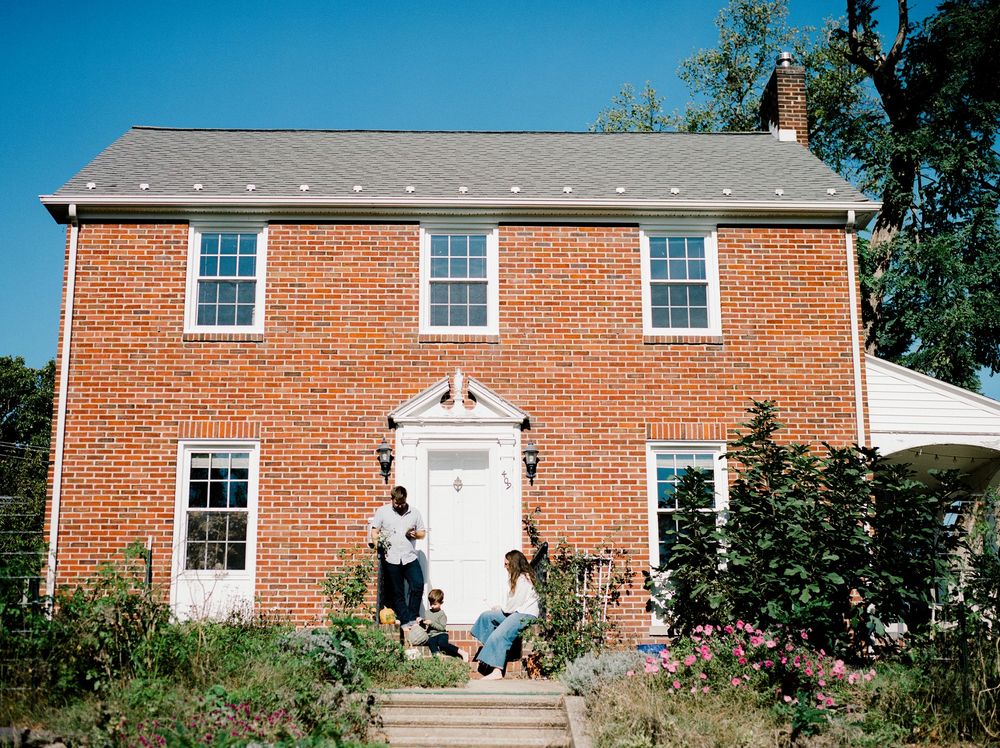 A panoramic view of red brick colonial houses with white trim and windows along a residential street.