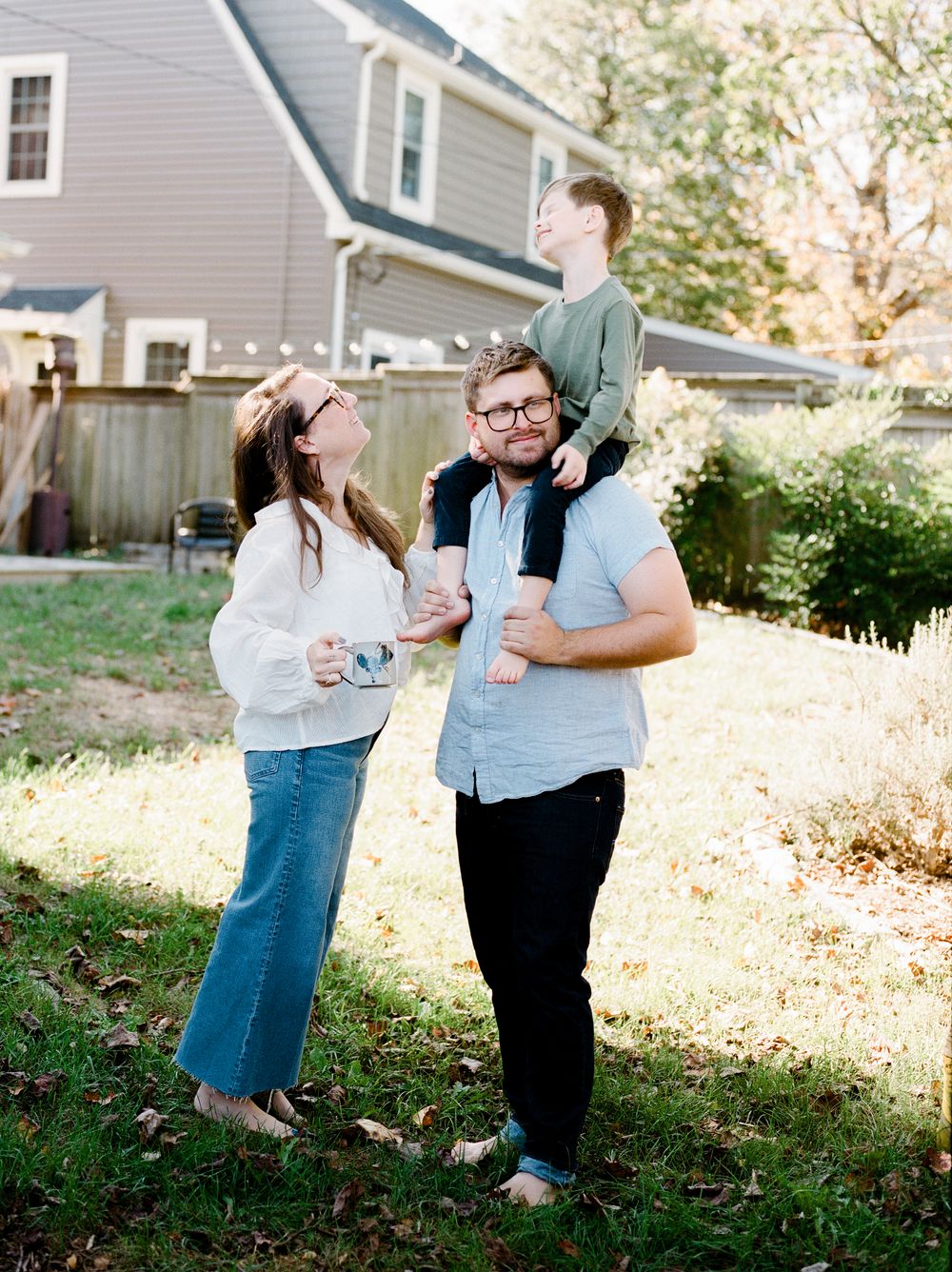Romantic outdoor engagement photoshoot in a sunlit backyard garden setting.