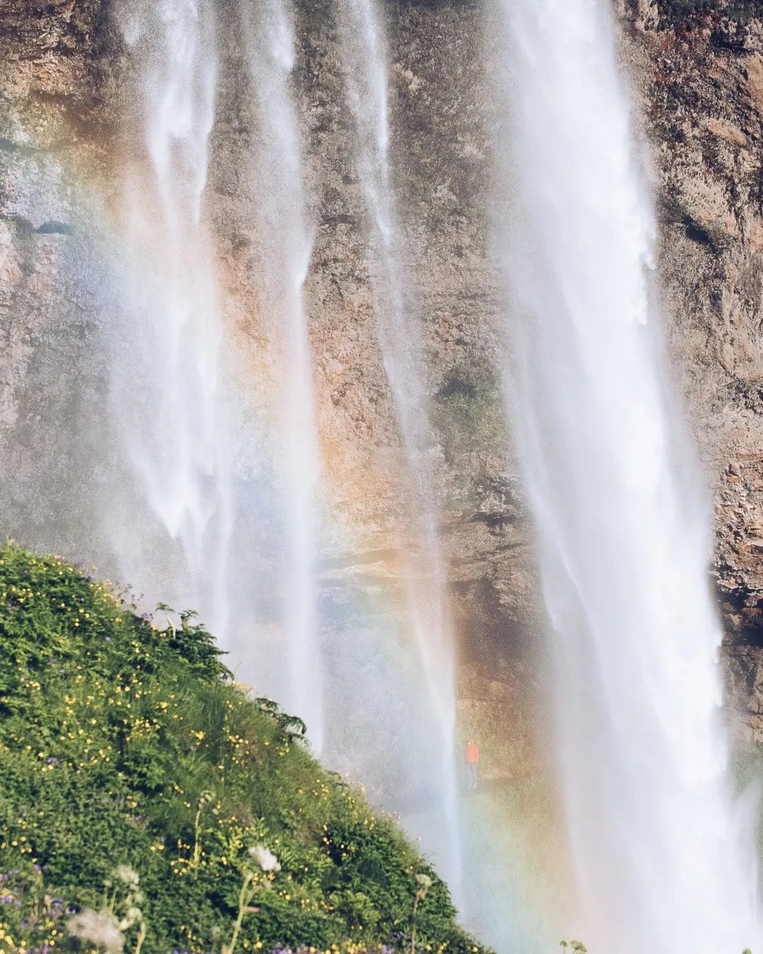 Icelandic waterfall with a small rainbow forming in the mist at its base.