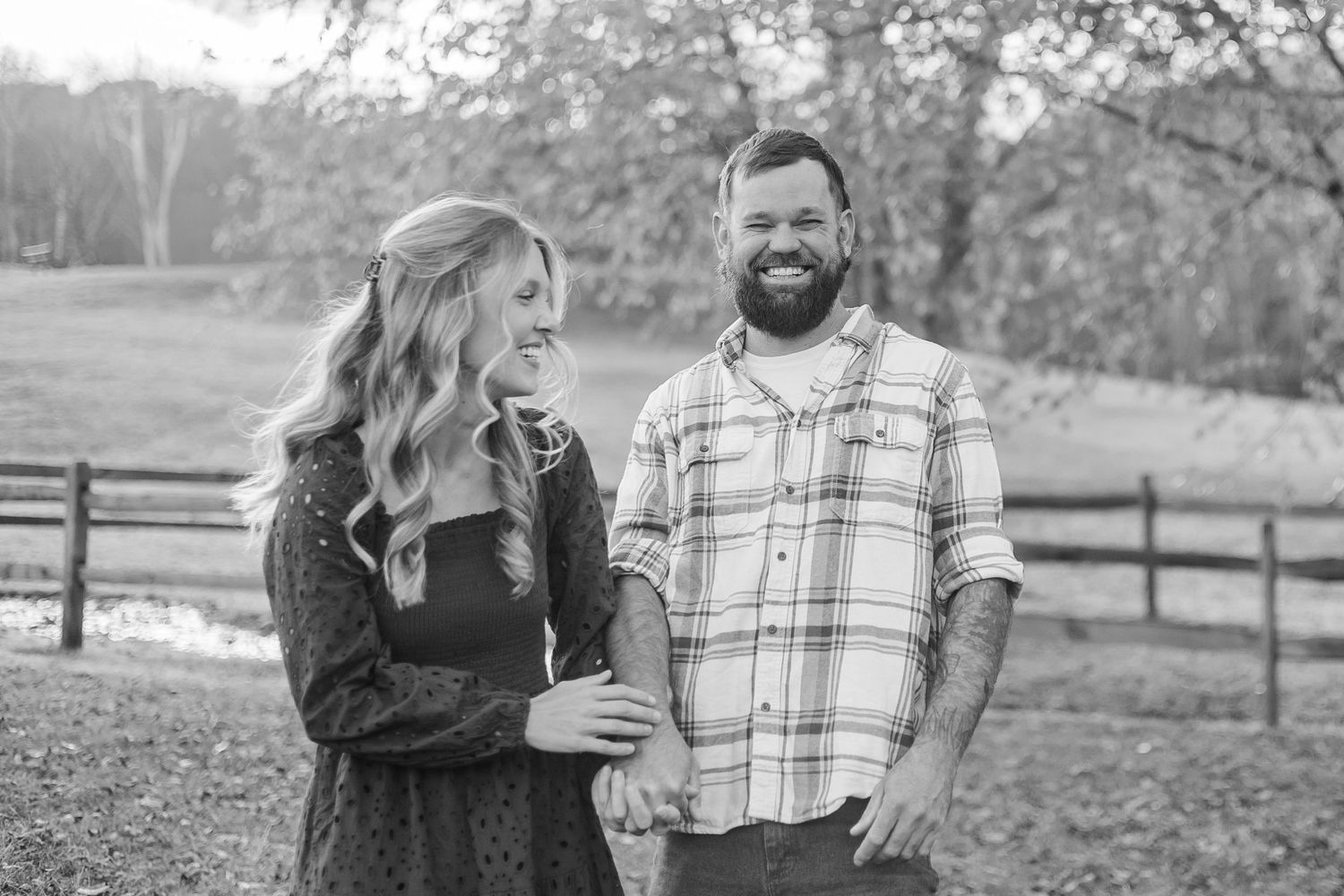 A couple walks together while laughing in a scenic outdoor setting through a series of candid black and white photojournalism