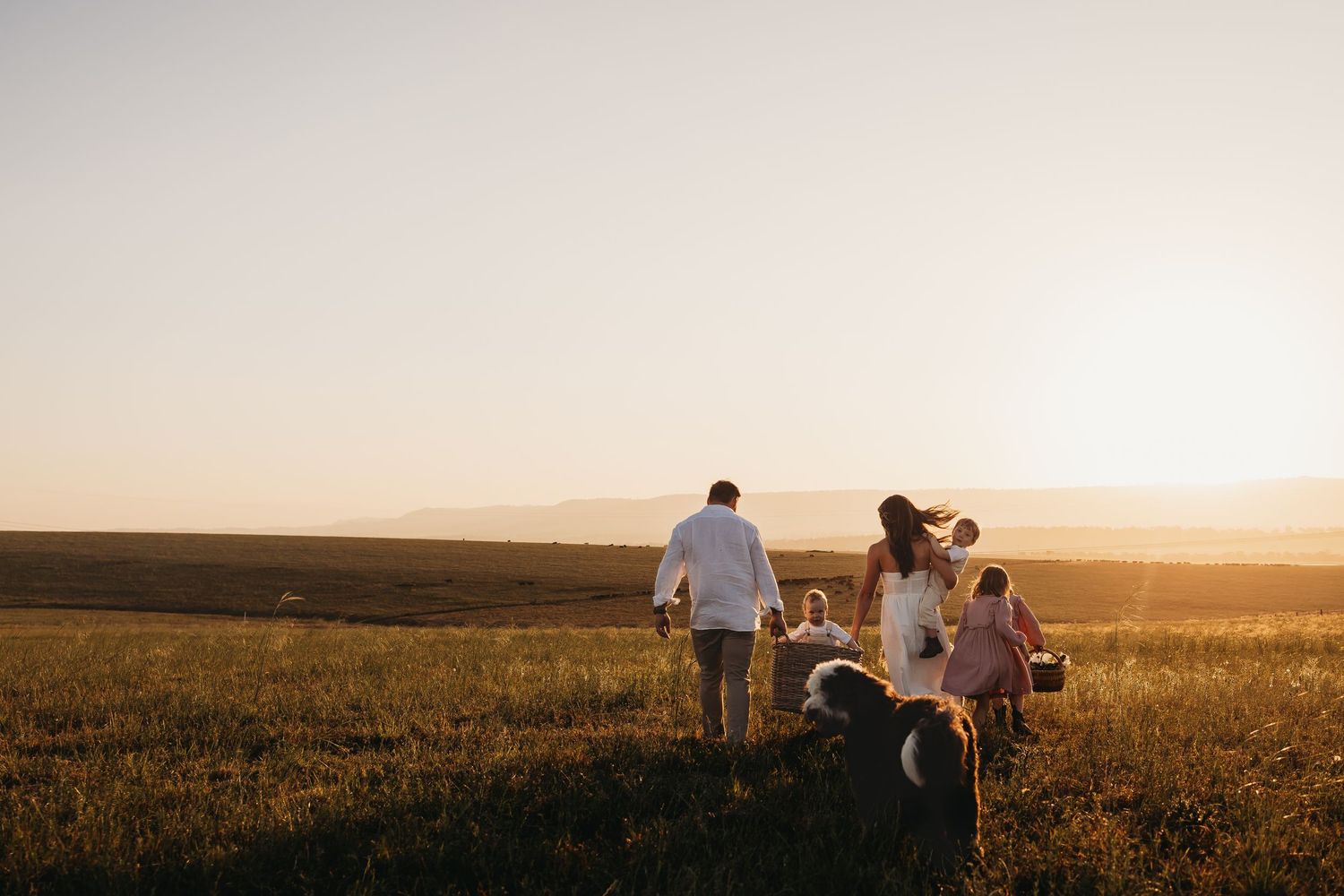 Family enjoying a picturesque sunset moment together in a golden field during magic hour.