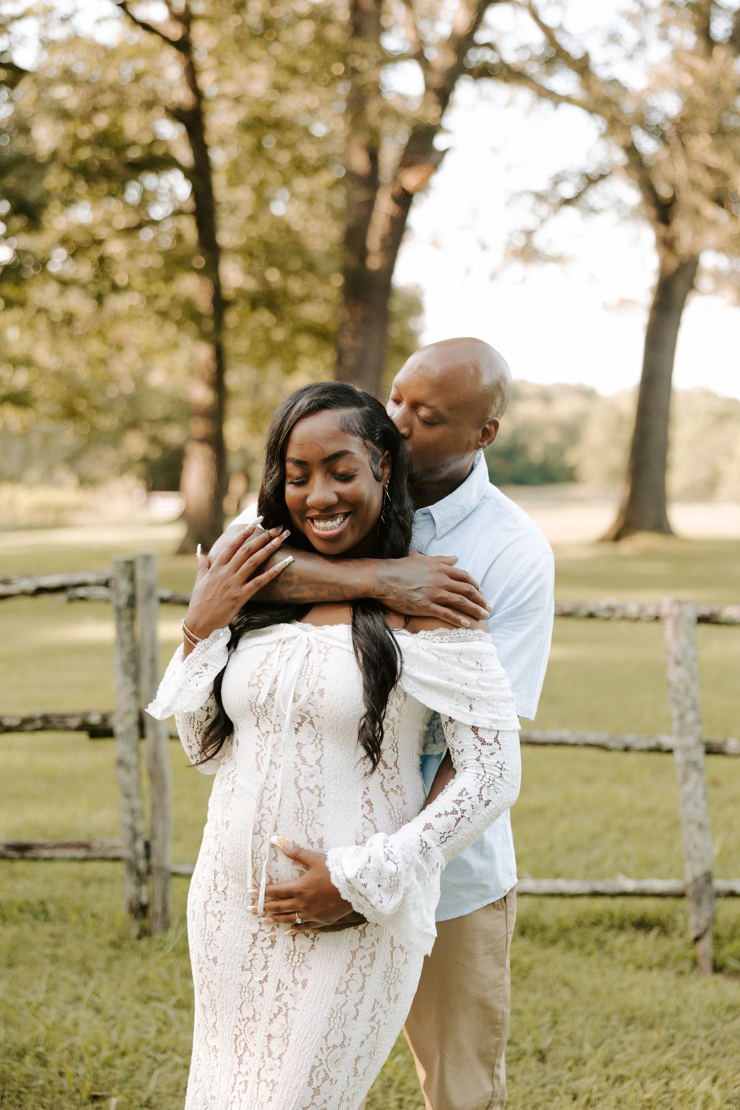 Joyful maternity photo session with couple in white clothing outdoors.