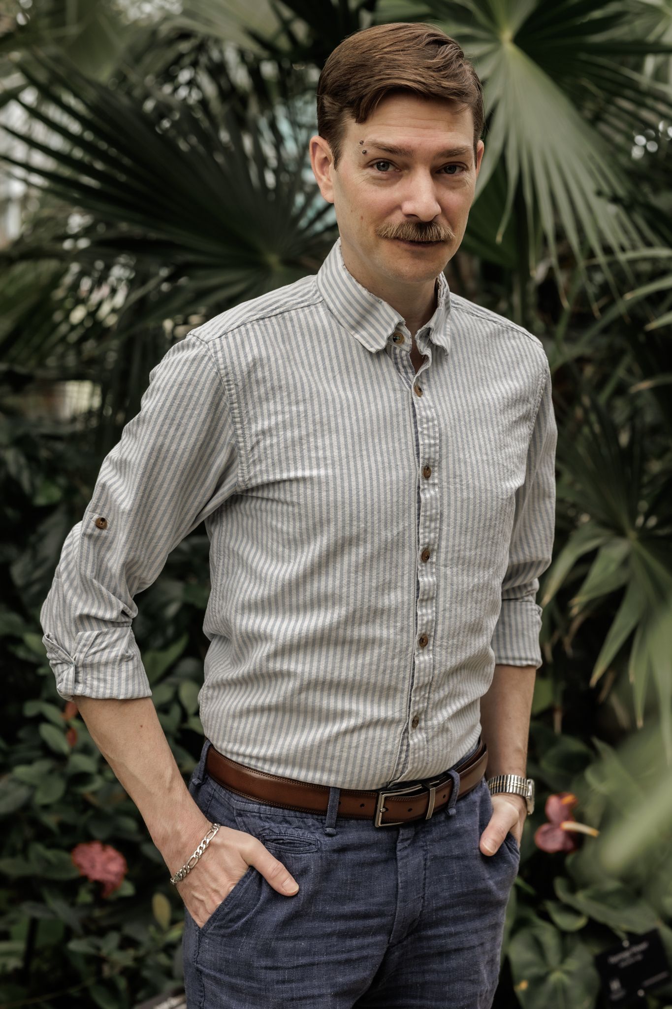 alternative headshot photo of a man against a lush background full of plants