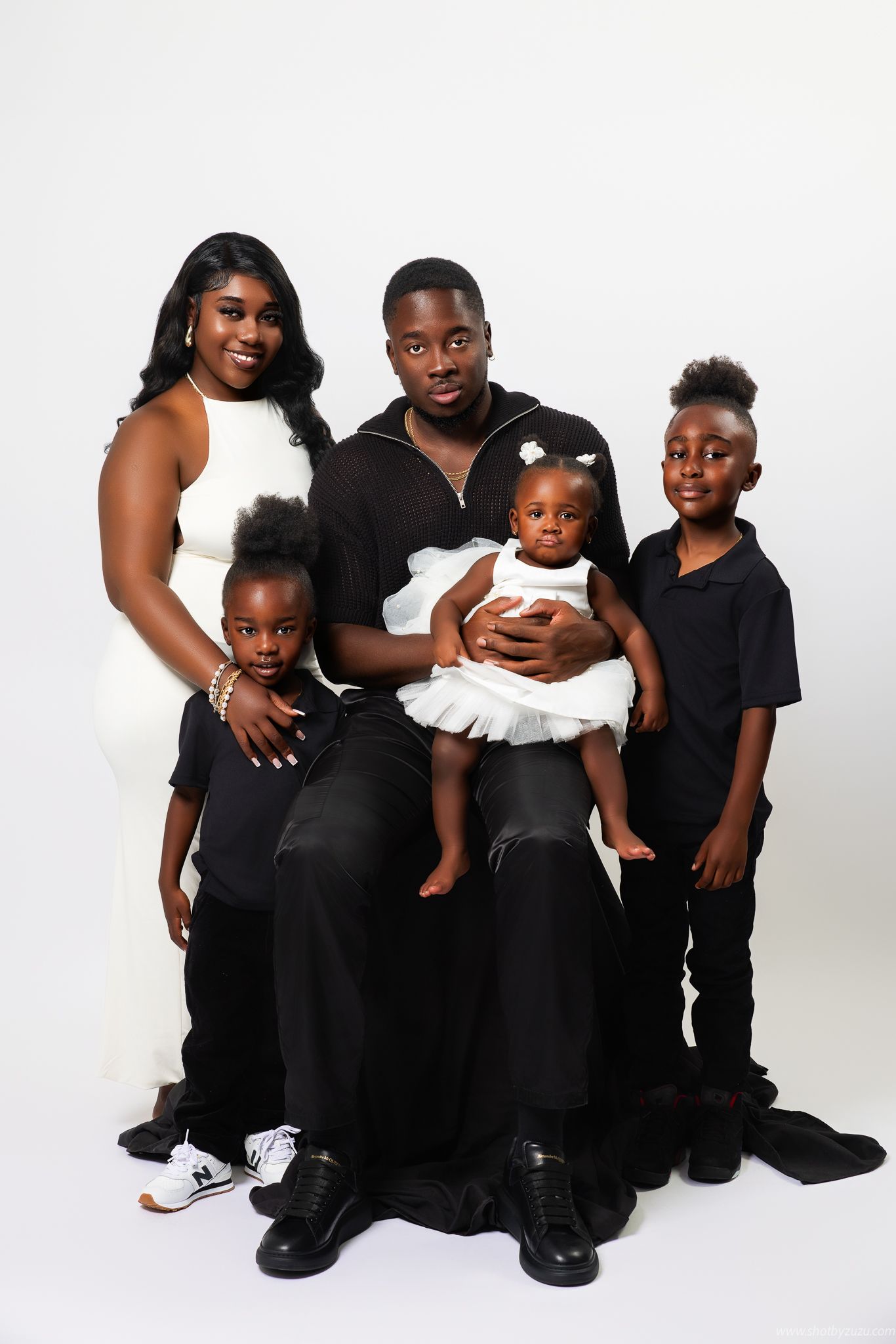 A family maternity photo series showing tender moments between parents and child against a neutral beige backdrop.