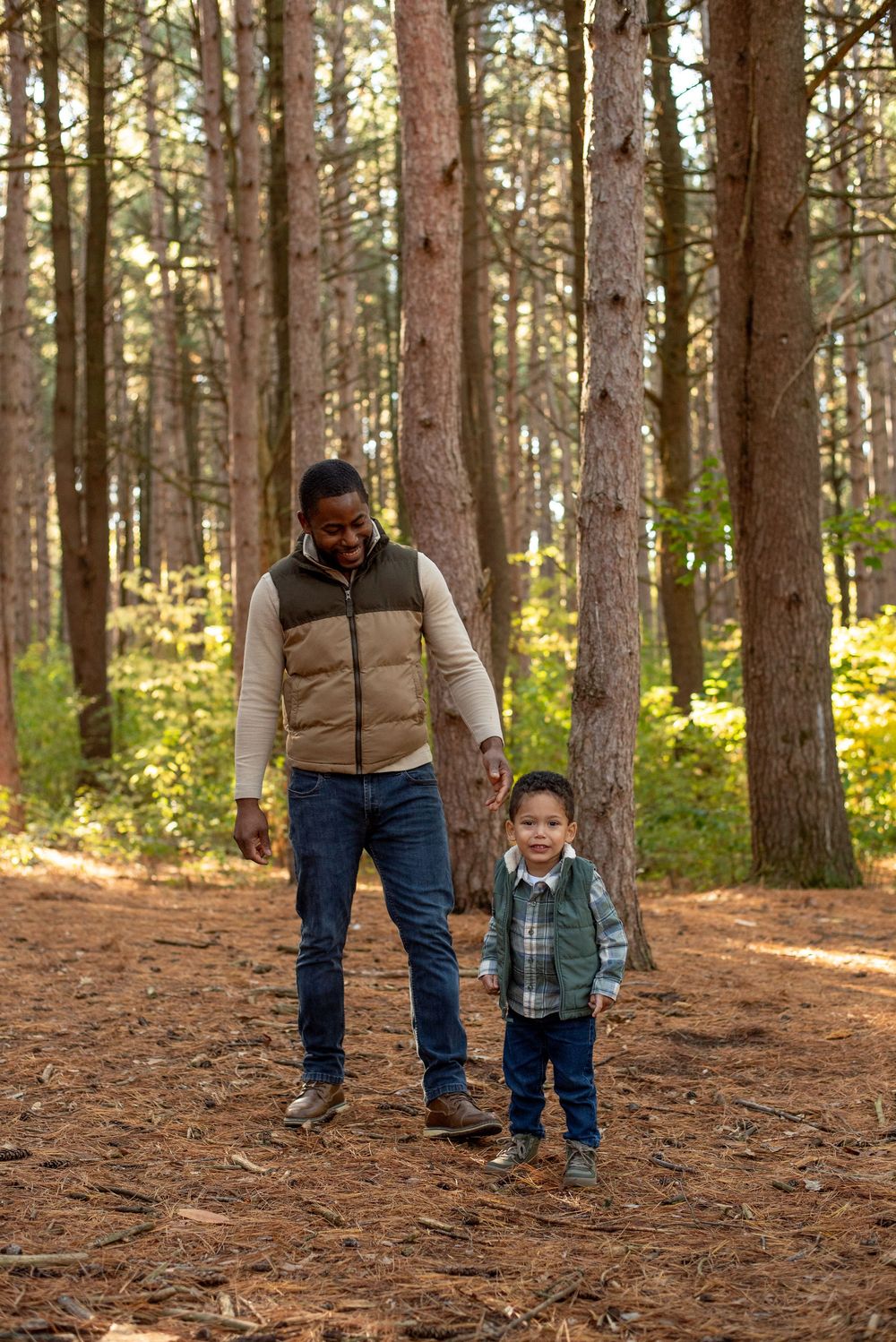 A dad and his oldest son walking together in a fall forrest in Grand Rapids, Michigan