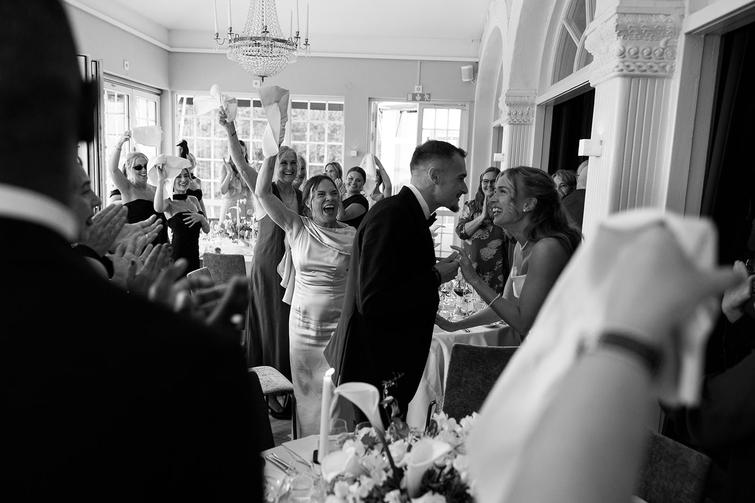 Wedding guests celebrate and dance together during a lively reception party at an indoor venue.