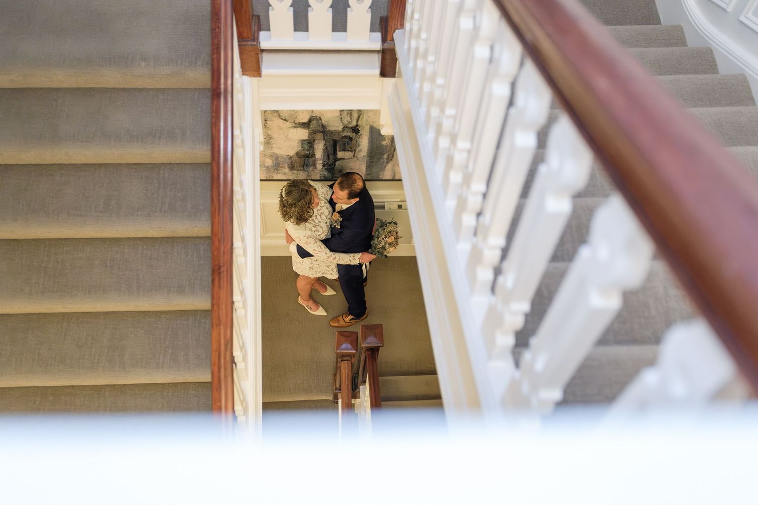 Multiple views of someone walking down beige carpeted stairs with white painted railings and wood banisters.