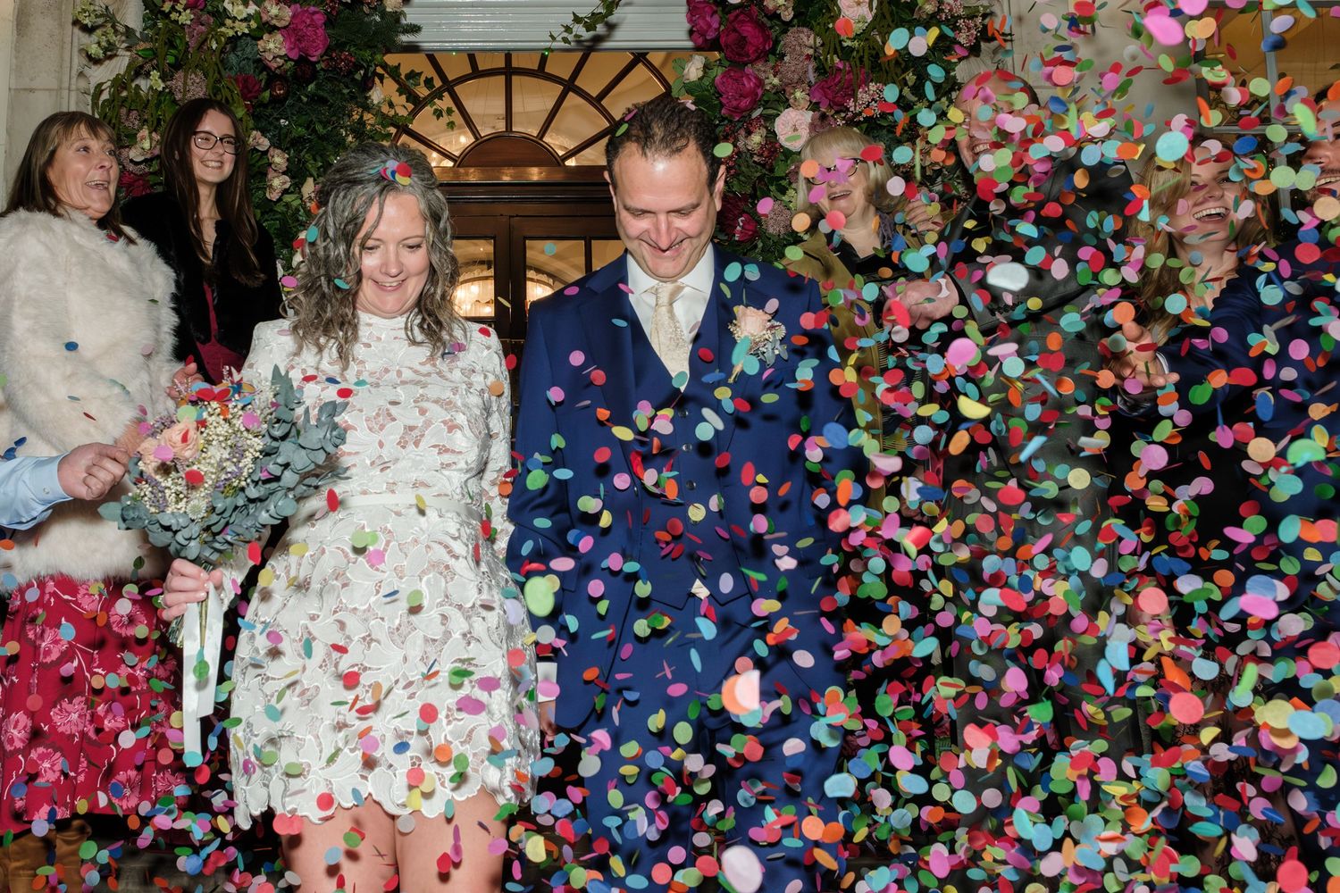 Colorful confetti rains down during a festive celebration with people gathered at an event.
