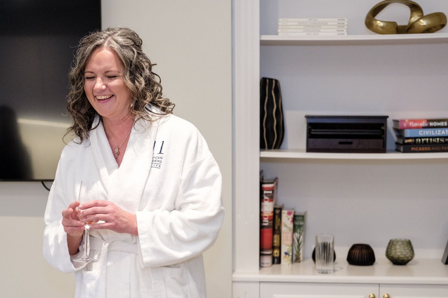 A person in a white robe smiles while getting their hair professionally styled in a bright salon.