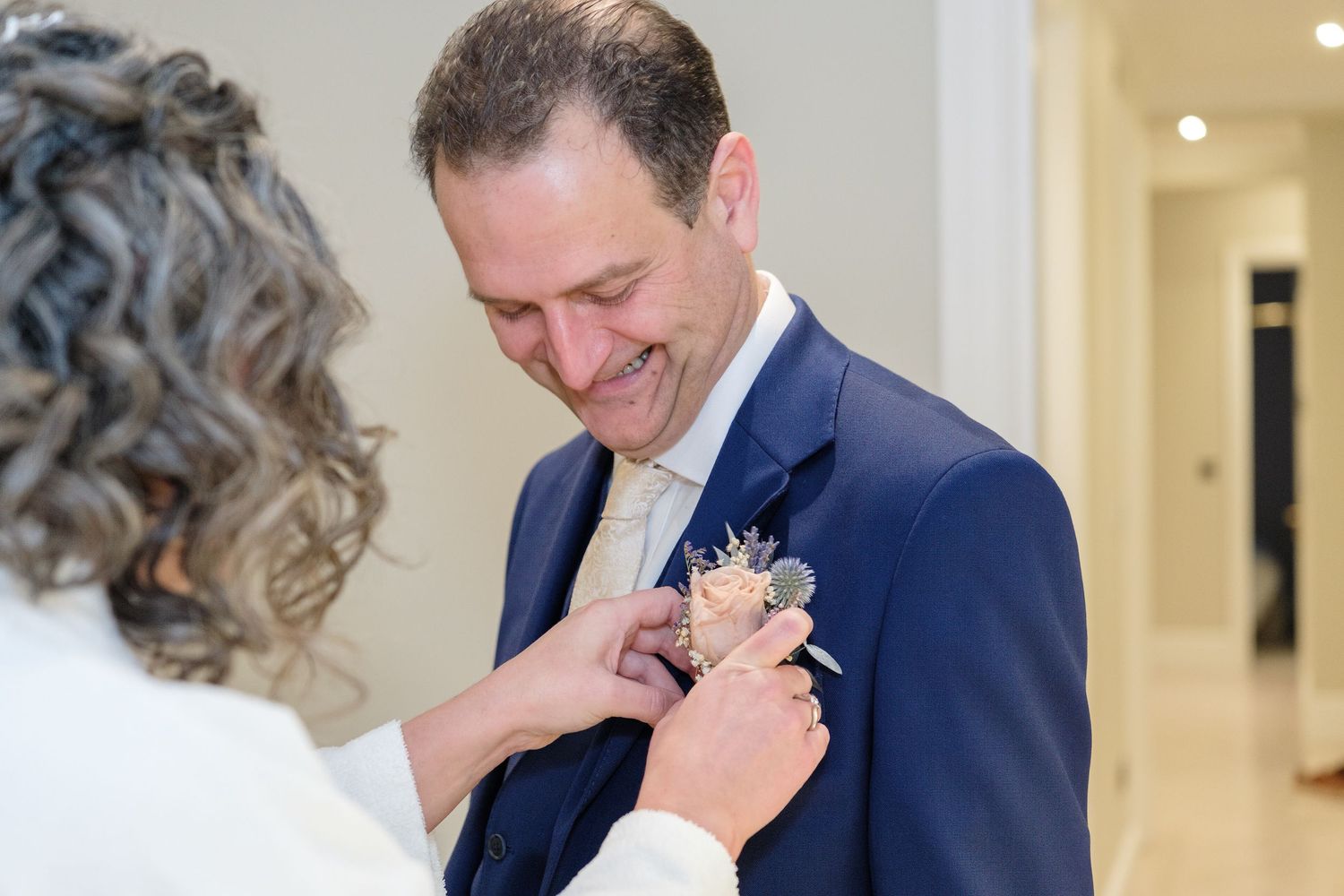 A couple in formal attire shares an intimate moment during a wedding celebration in an elegant hallway.