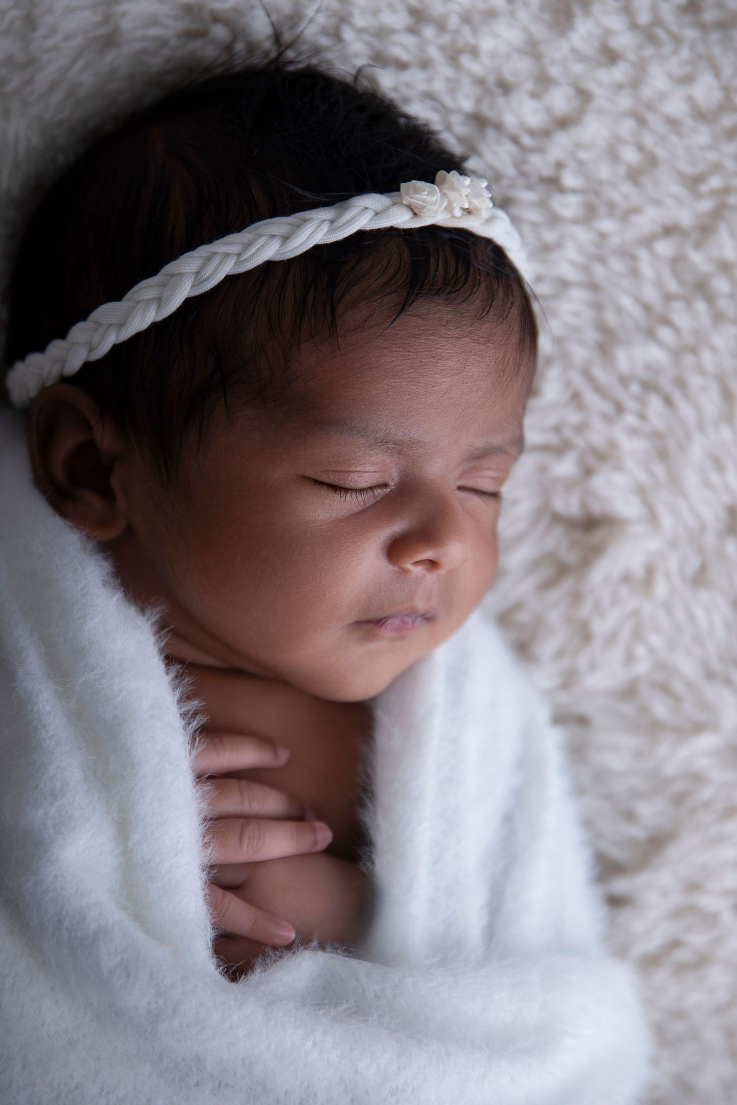 Professional newborn portrait in Gilston home studio with soft cream textures.