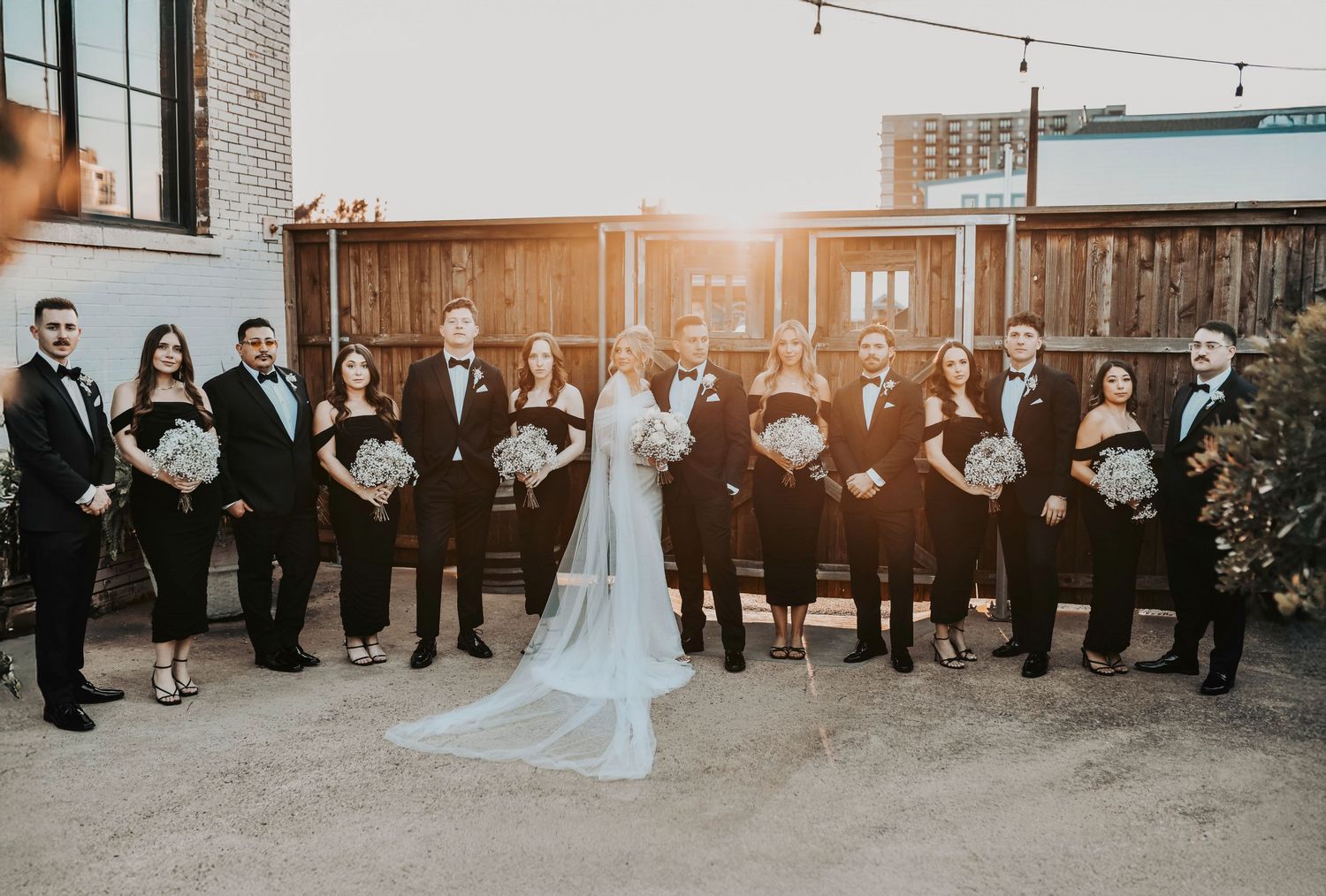 Bridal party celebrating at sunset with authentic laughter and movement, captured in golden-hour glow in Deep Ellum Dallas.