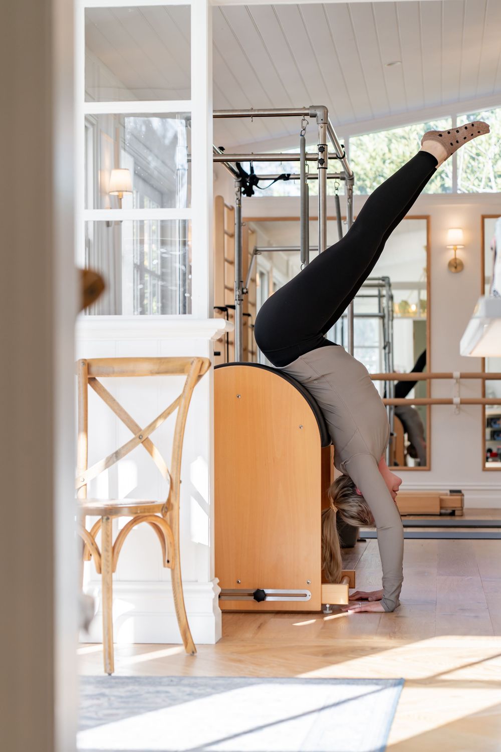 Person demonstrating a pilates exercise sequence on reformer equipment in a bright studio setting.
