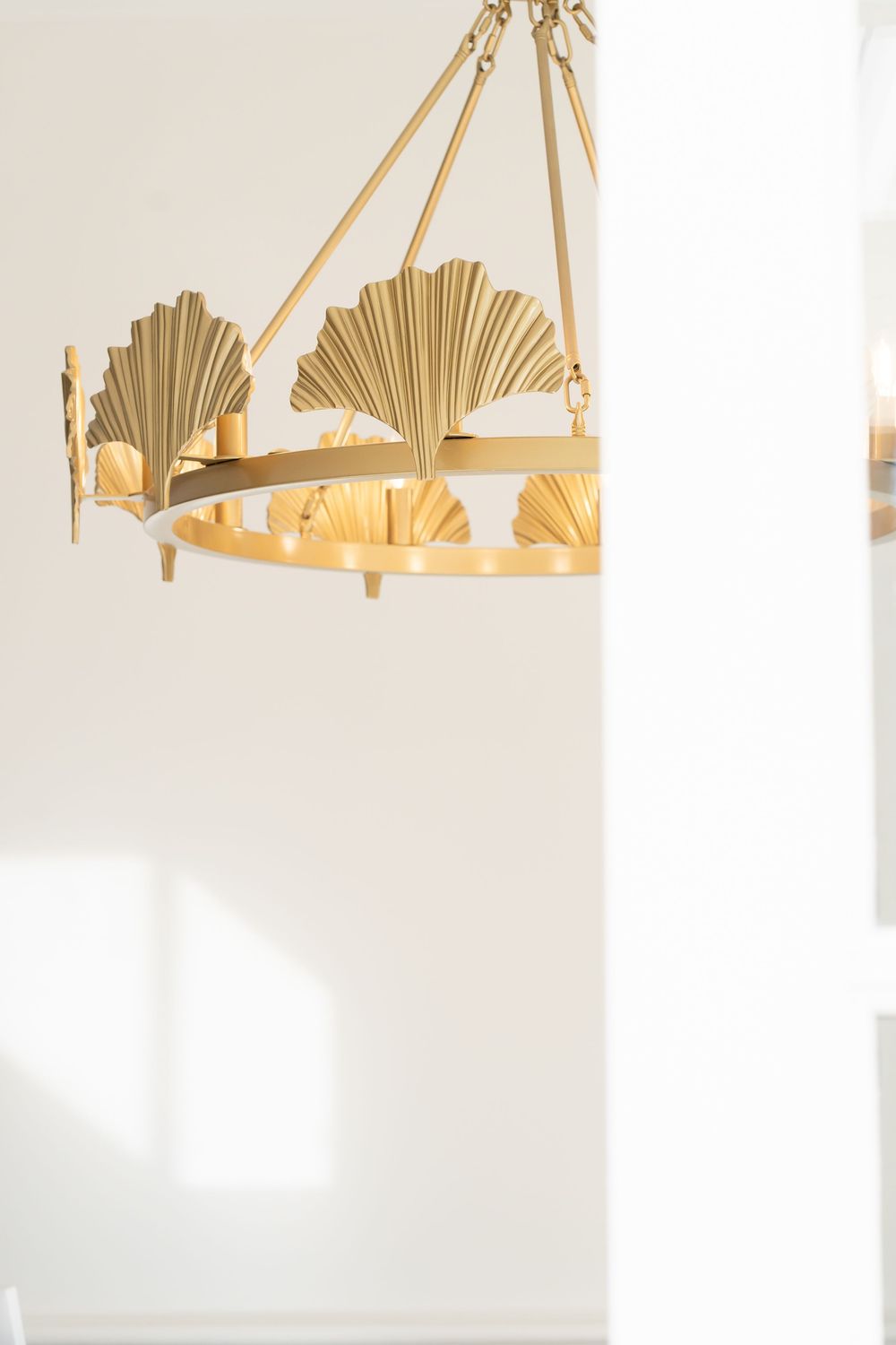 Elegant gold fan-shaped chandeliers hanging from a white ceiling in a bright modern interior space.