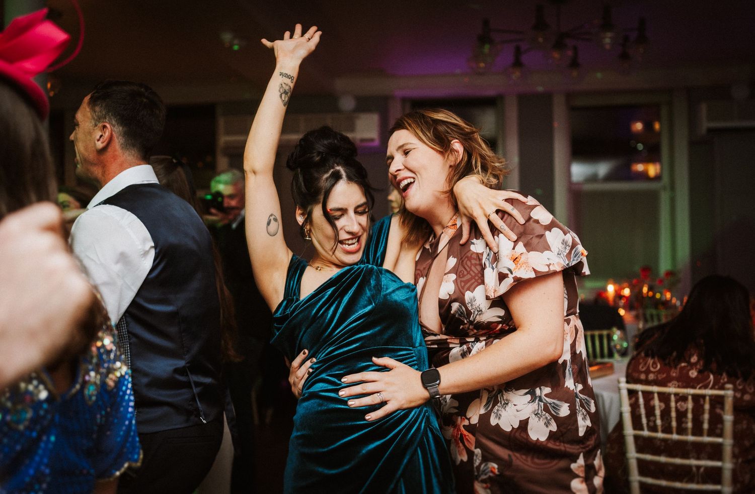 Dance floor filled with guests celebrating at an evening wedding reception with purple lighting.