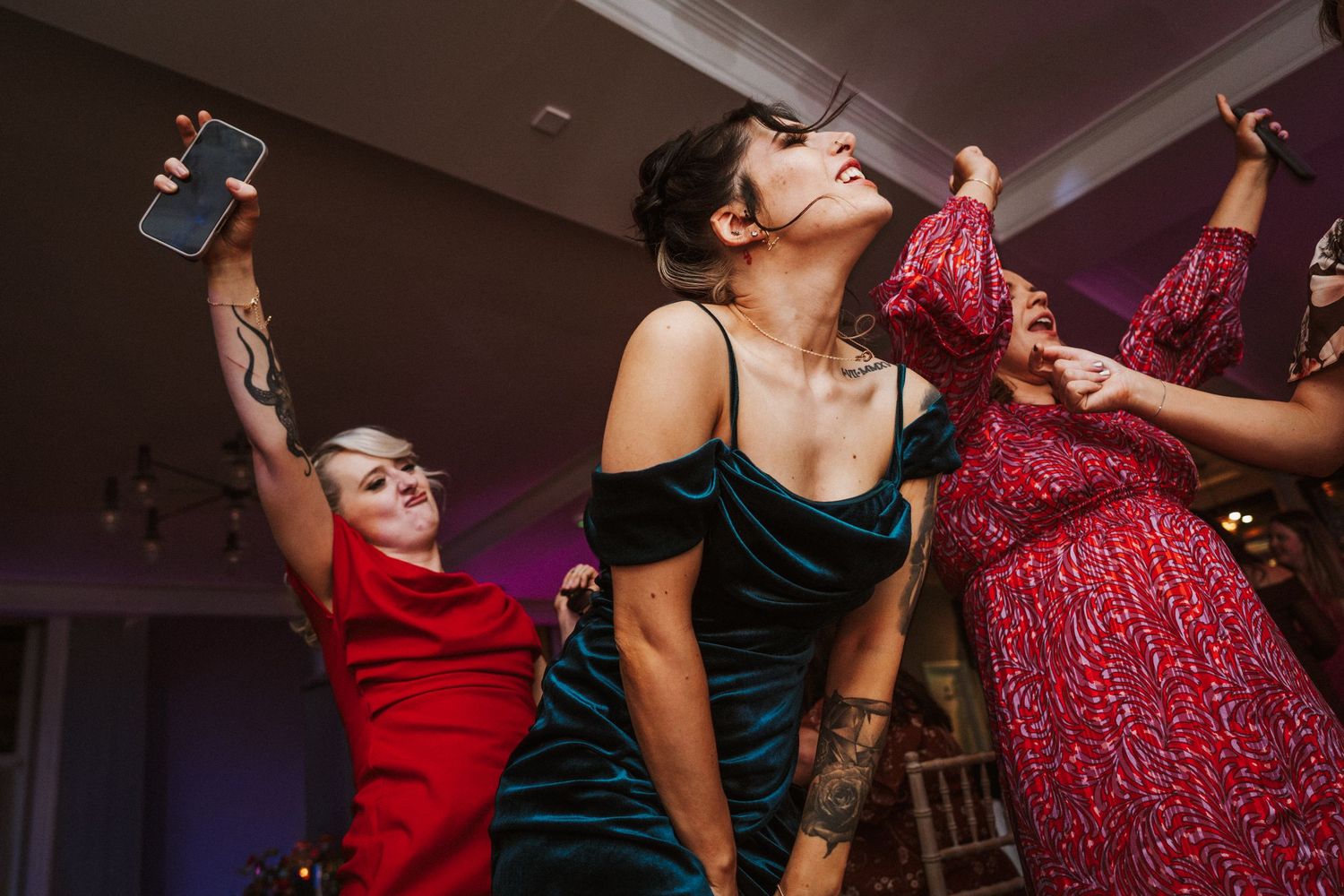 Wedding reception dance floor filled with energetic guests in colorful dresses.
