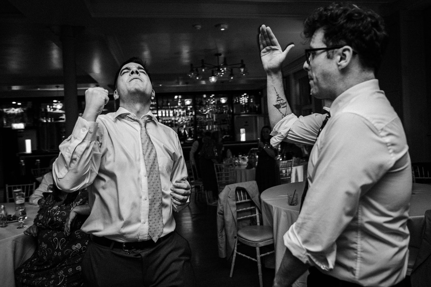 Black and white candid shots of guests mingling and celebrating at an indoor wedding reception.