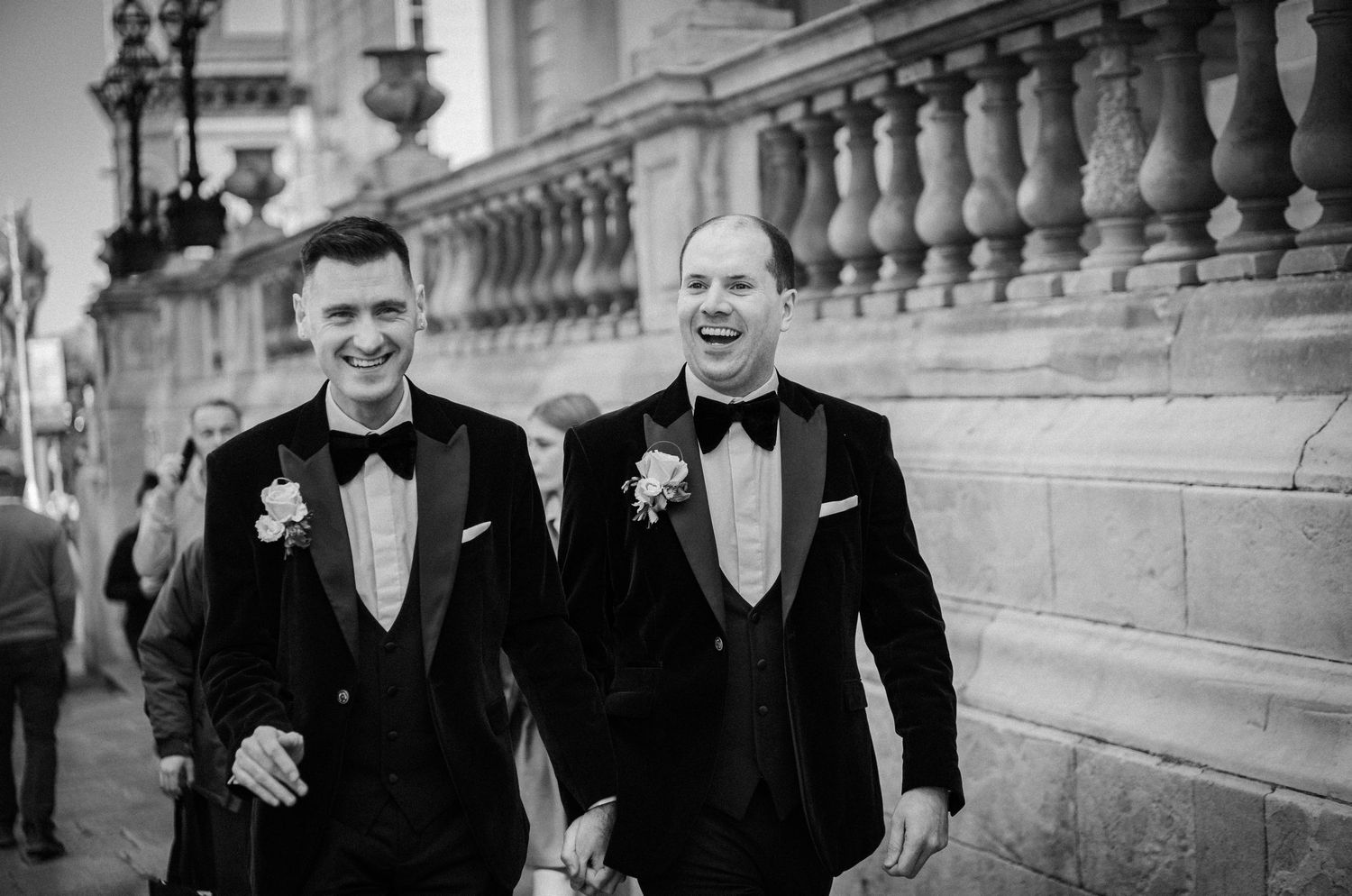 Guests in formal attire gather outside a grand columned building during a wedding celebration.