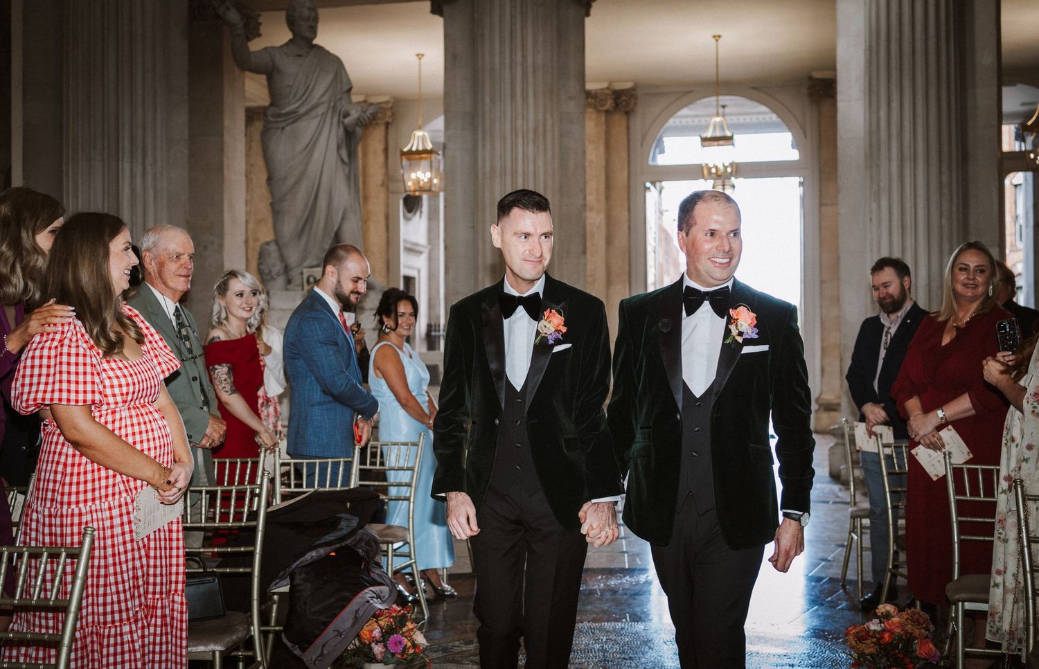 Wedding ceremony guests seated in elegant venue with classical architectural details.