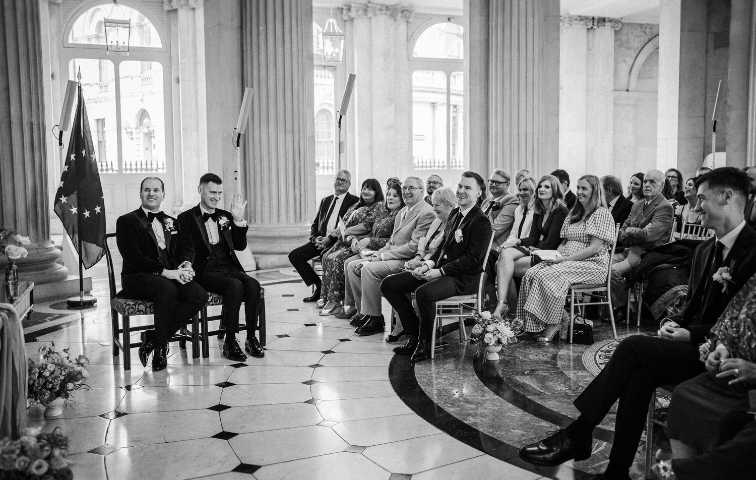 Wide view of wedding ceremony seating with white chairs arranged between ornate columns.