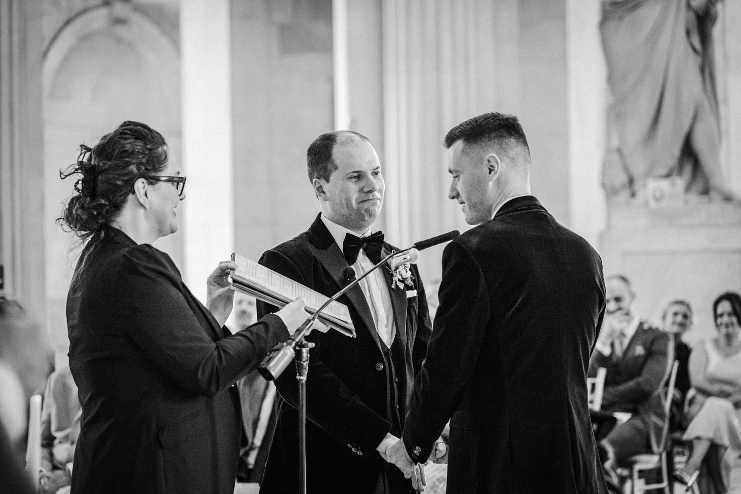 Black and white photos capturing emotional moments during a formal indoor wedding ceremony.