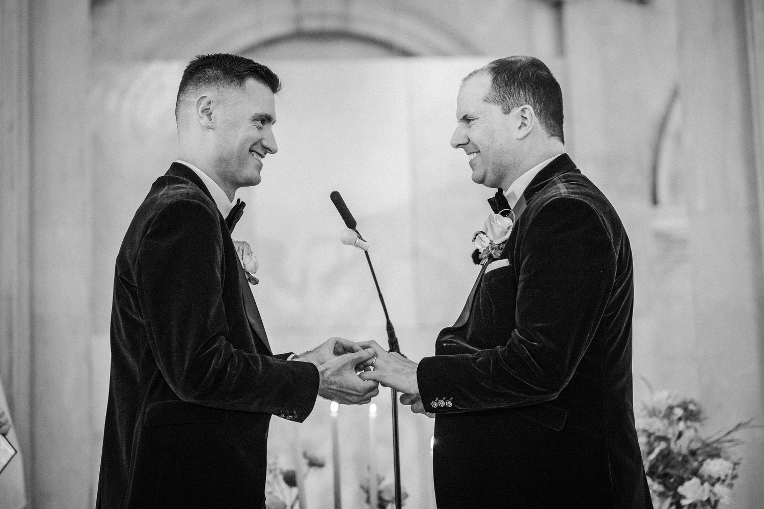 Formal wedding party members interact in an elegant venue with classical architecture.