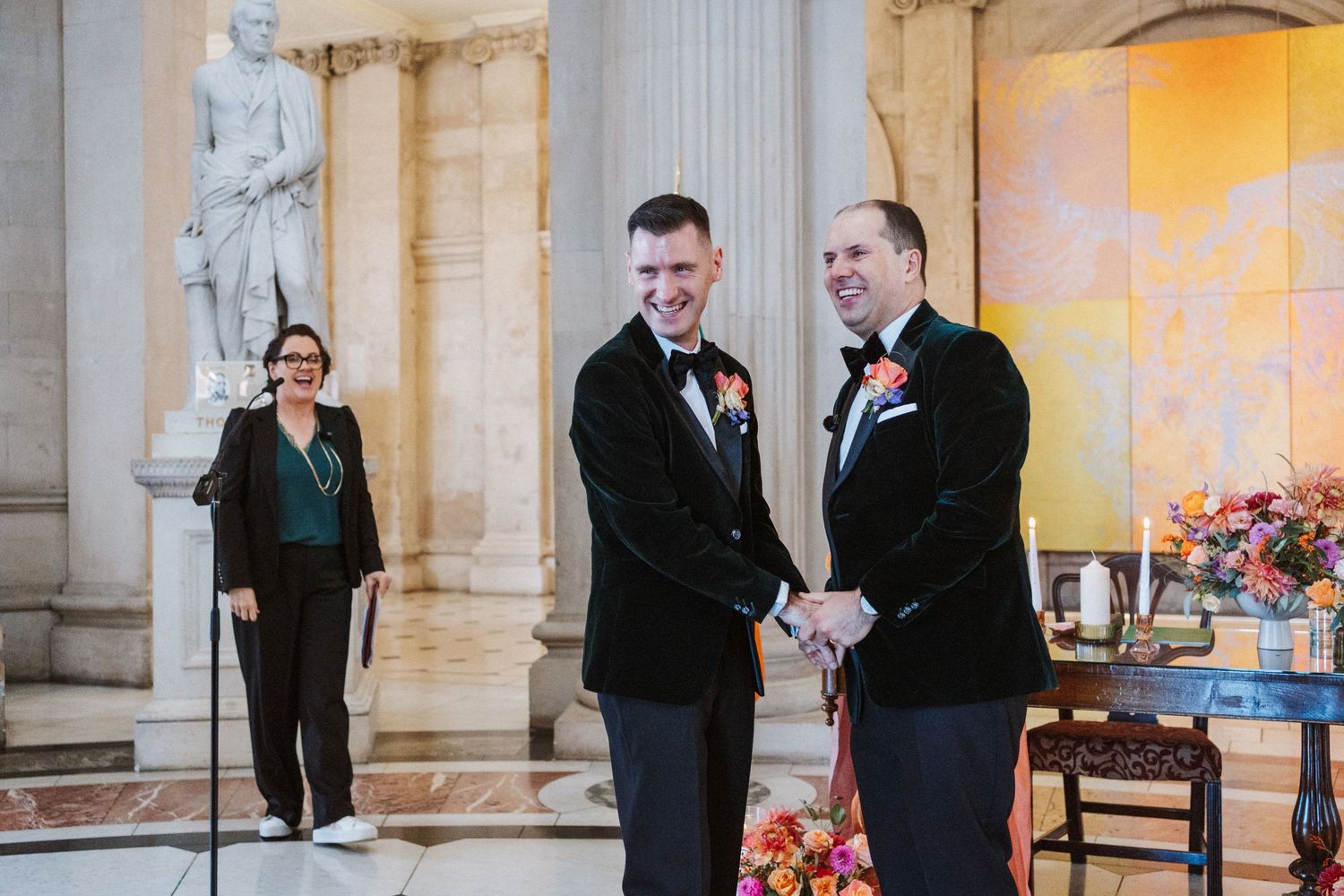Elegant wedding ceremony setup in classical building with stone columns and warm lighting.
