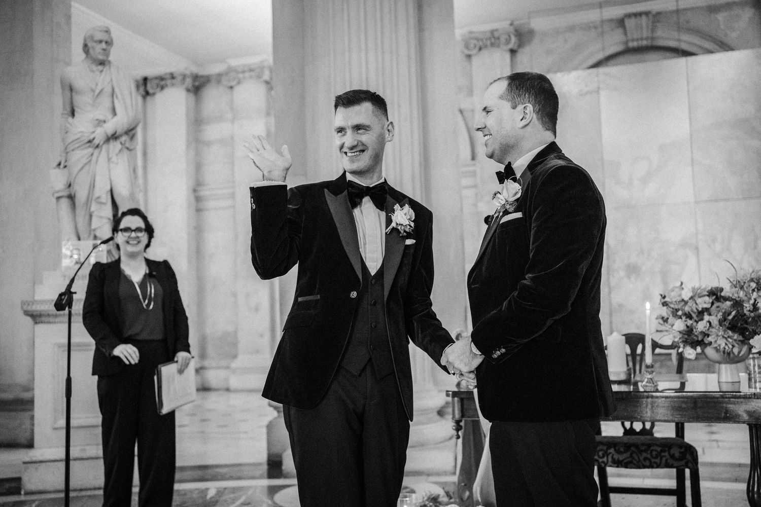 Black and white photo of formal gathering in an elegant columned venue.
