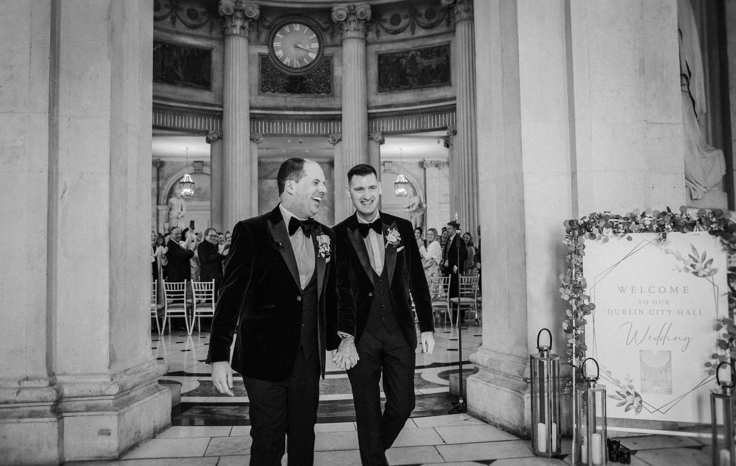 Black and white wedding photo series showing emotional moments in a grand columned venue.