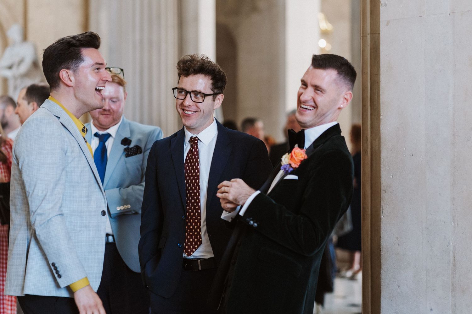 People in business attire having a conversation in a hallway with columns.