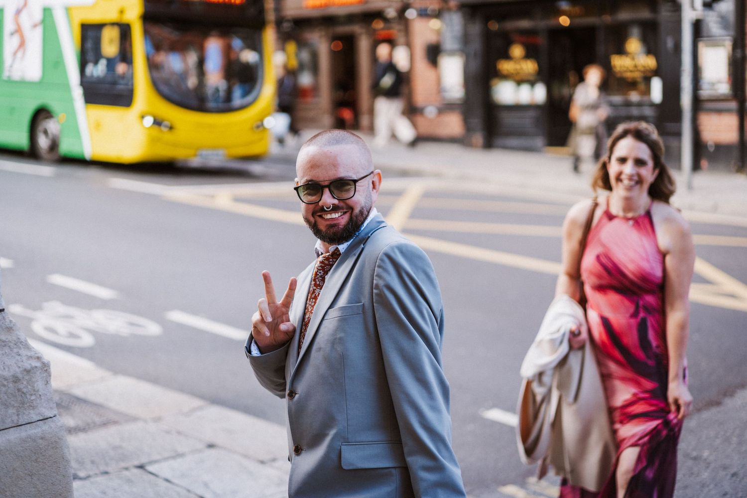 Couple walking together on a city street with a yellow bus visible in the background.