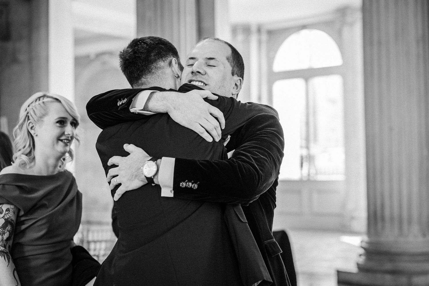 Tender embraces between wedding guests captured in black and white photography at an elegant venue.