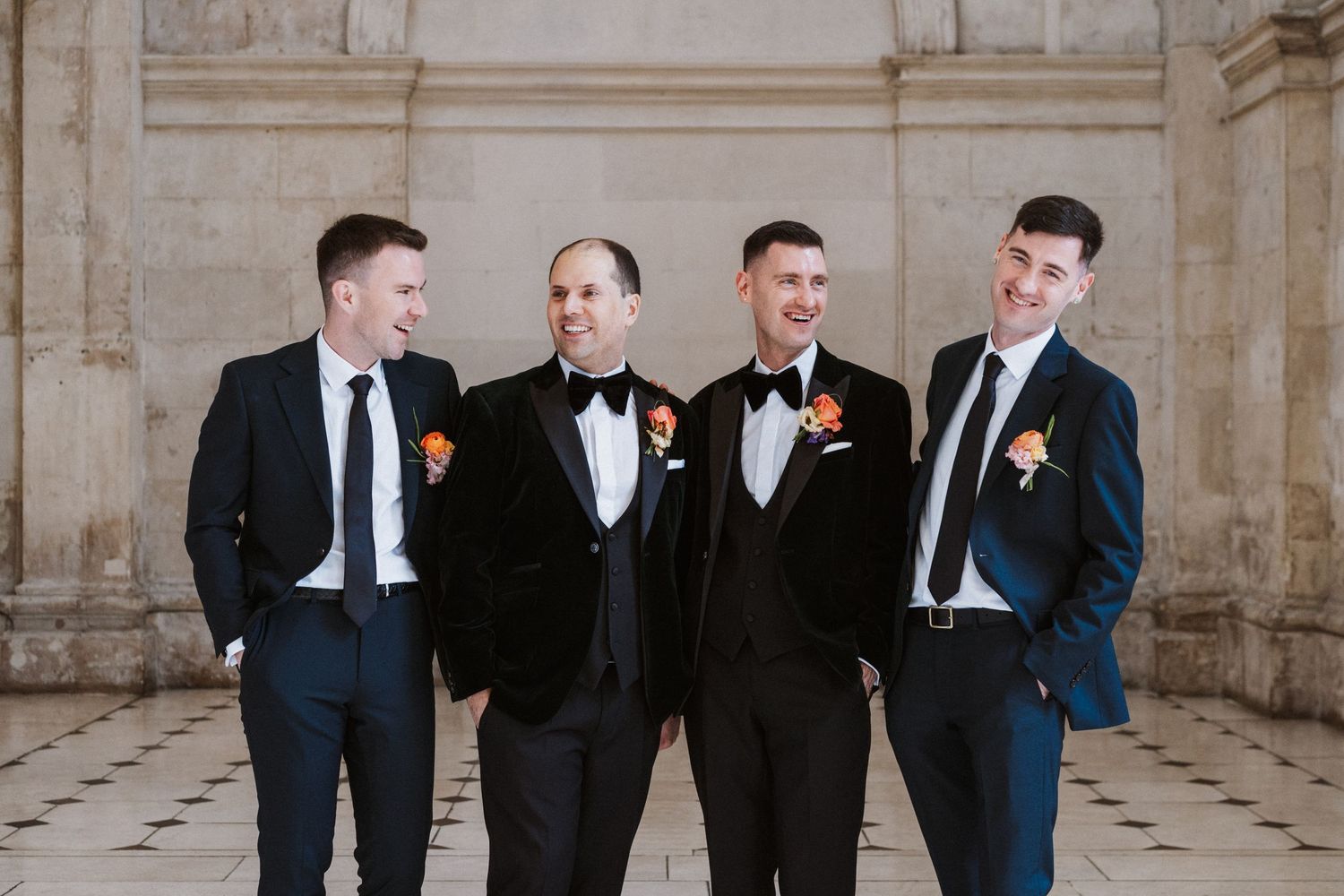 Wedding party members in formal attire gathered in classical architectural setting.