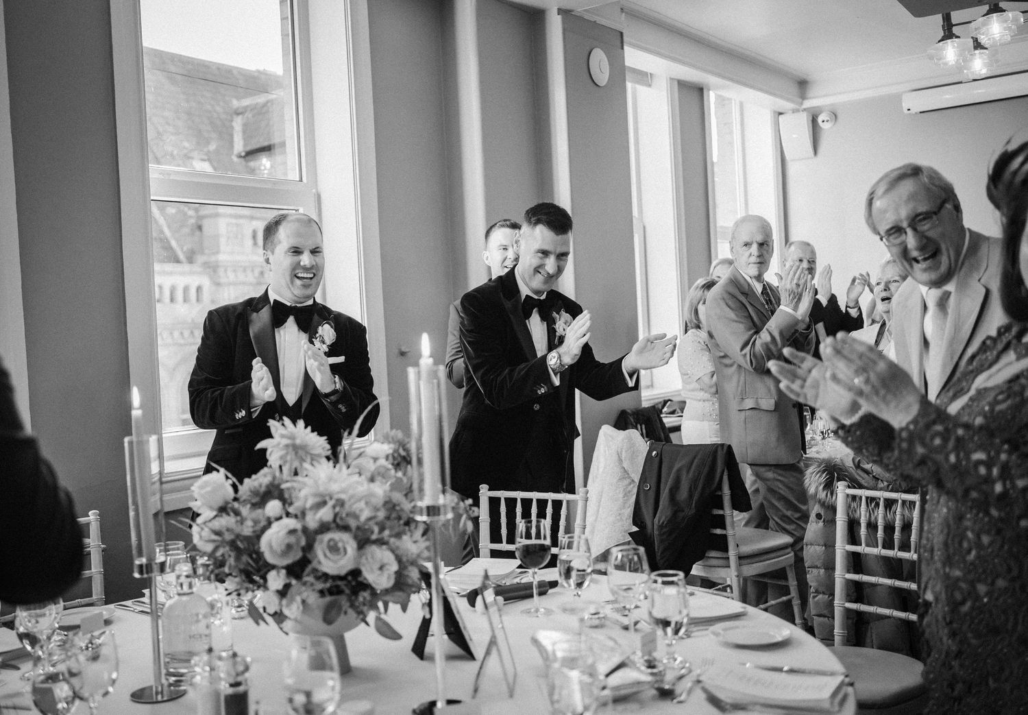 Wedding guests enjoying a formal dinner reception at elegantly decorated tables with floral centerpieces.