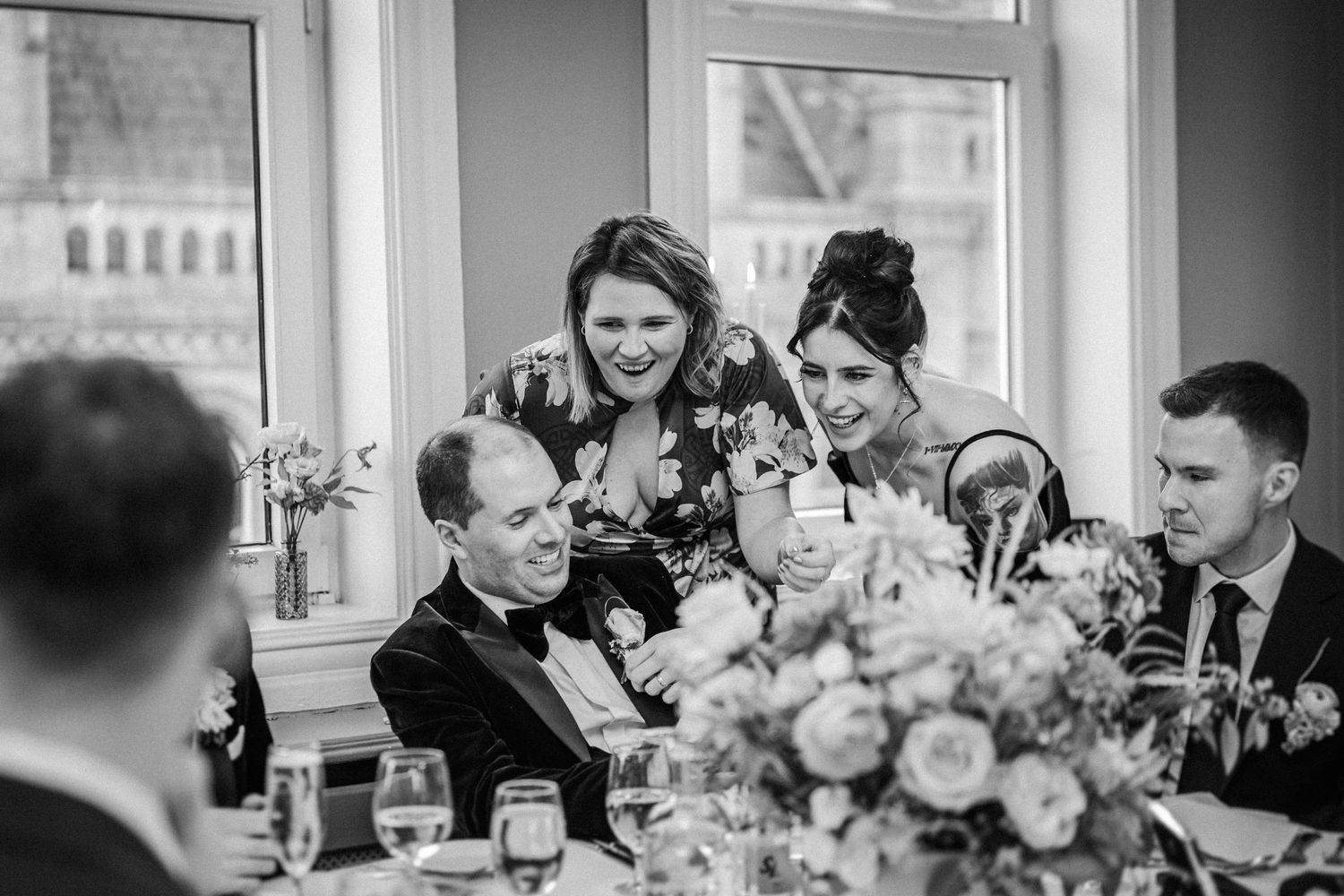 Reception guests seated at round tables with elegant floral arrangements and glassware.