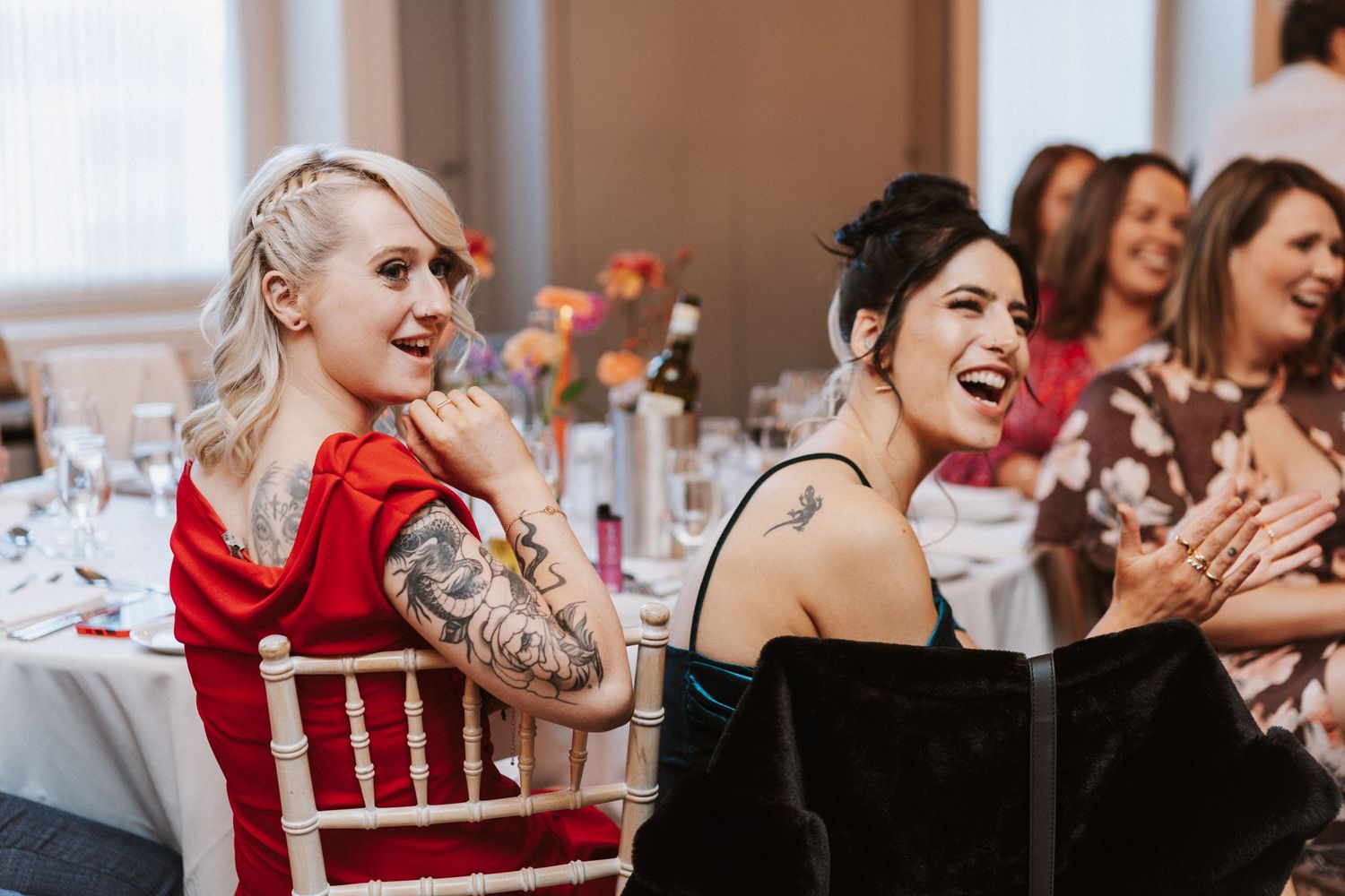 Wedding guests laugh and celebrate together during a joyful reception moment.