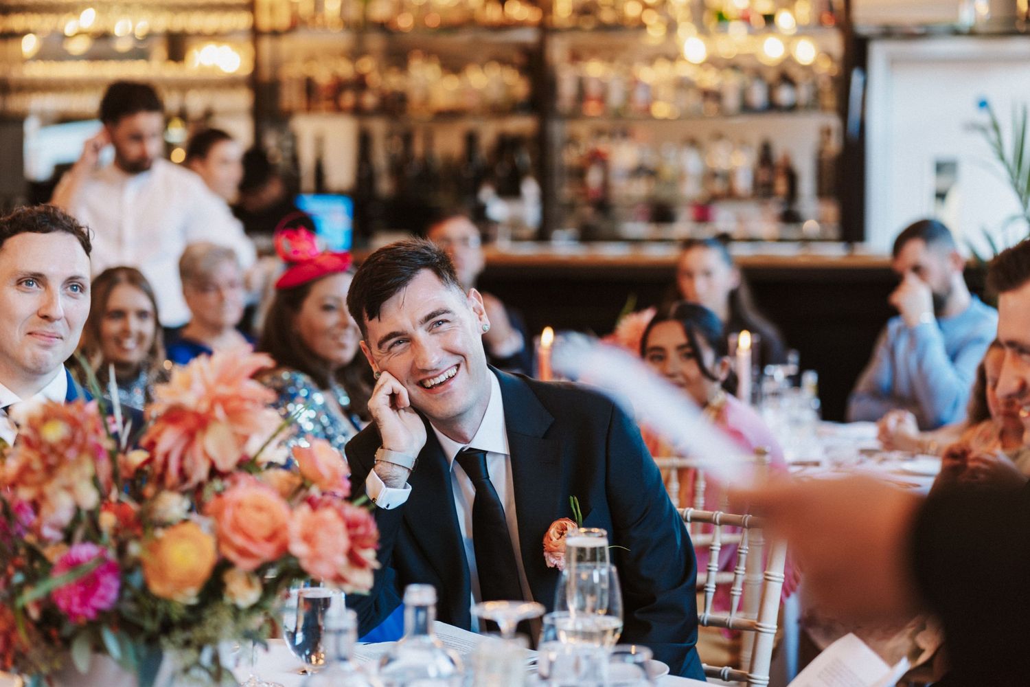 Wedding reception venue decorated with warm lighting and colorful floral arrangements on dining tables.