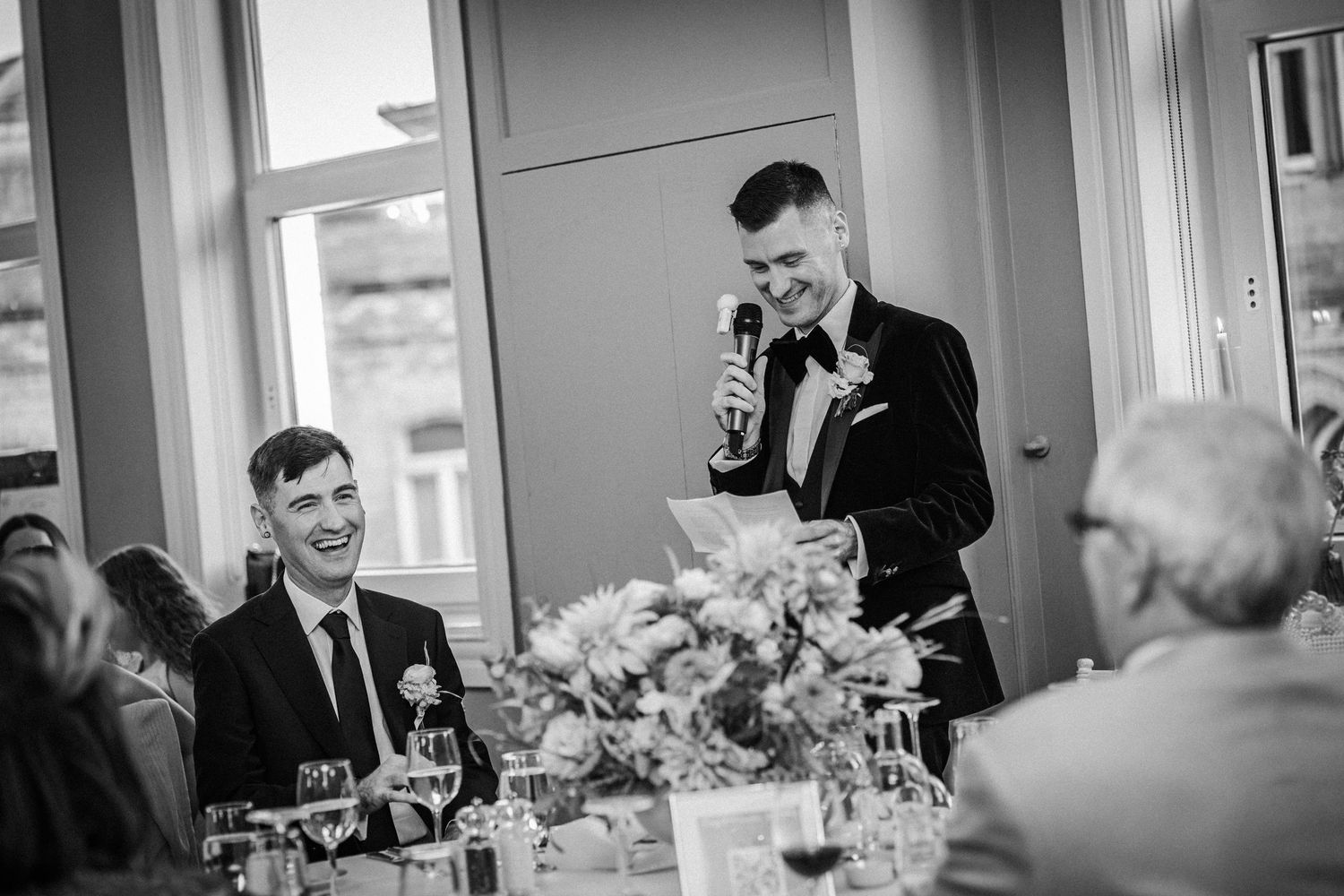 Wedding guests laughing and celebrating during an indoor reception with festive lighting and decorations.