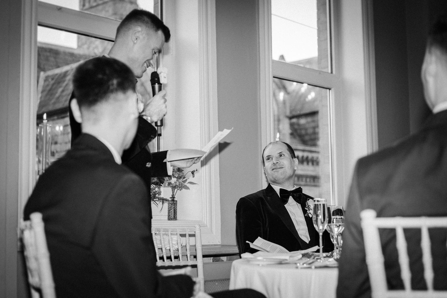 Wedding celebration candid moments captured in black and white at an elegant indoor venue.