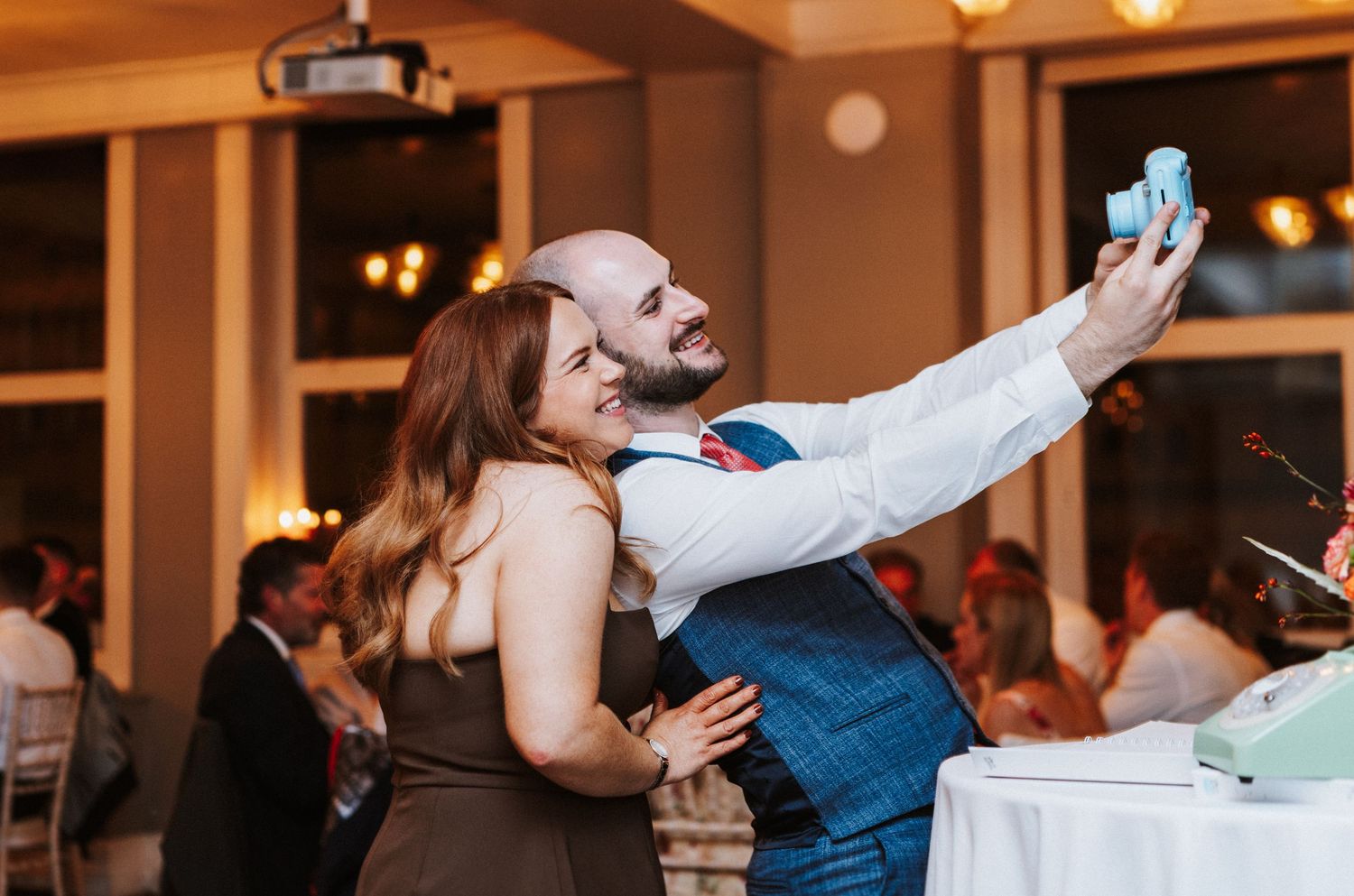 Wedding guests dancing and celebrating at a lively reception with warm lighting and festive atmosphere.