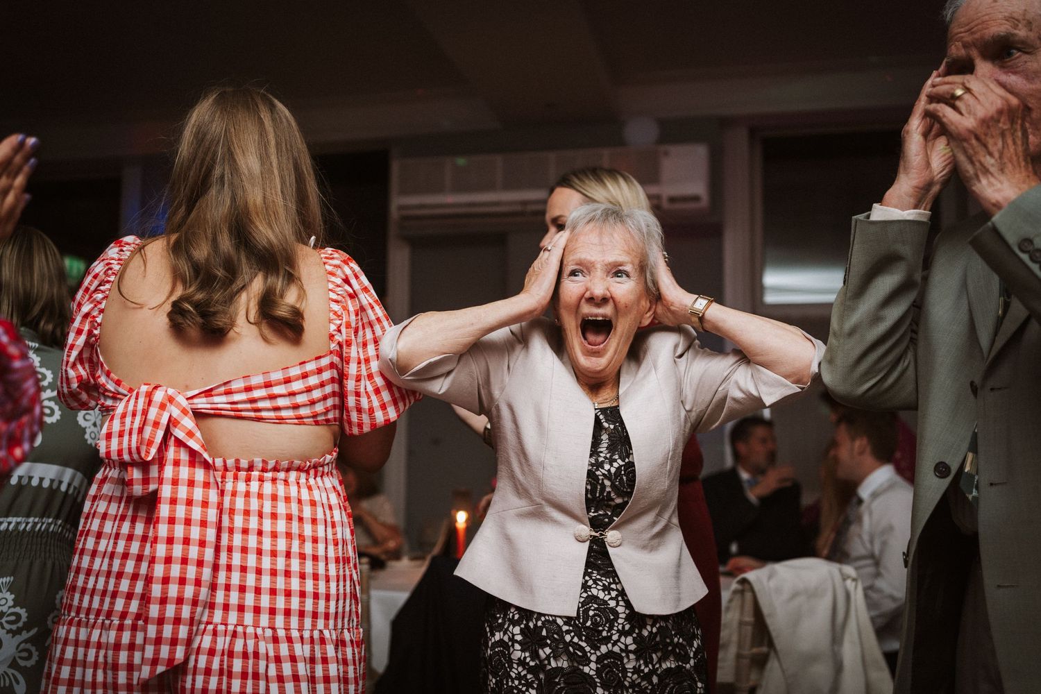 Guests showing animated expressions during fun wedding reception moments.