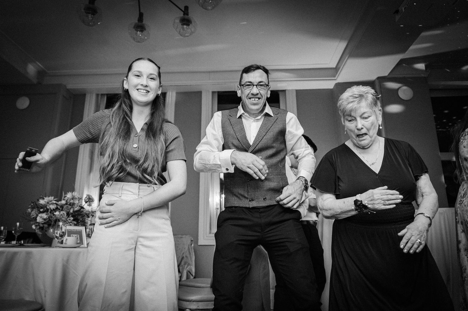 Black and white photo of wedding guests enjoying themselves during a lively reception party.