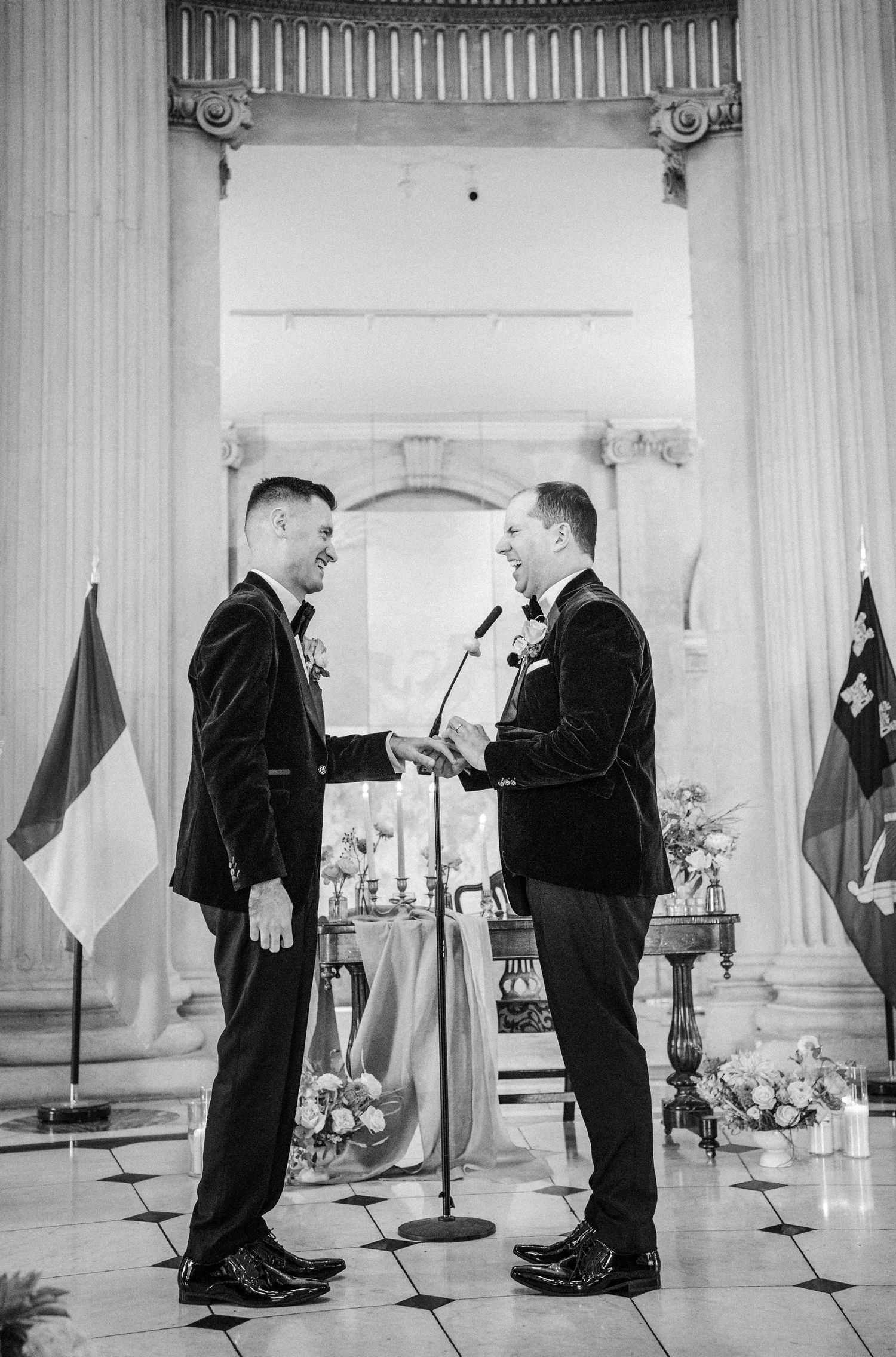 A series of black and white photographs showing two men in suits speaking at microphones in a formal setting.