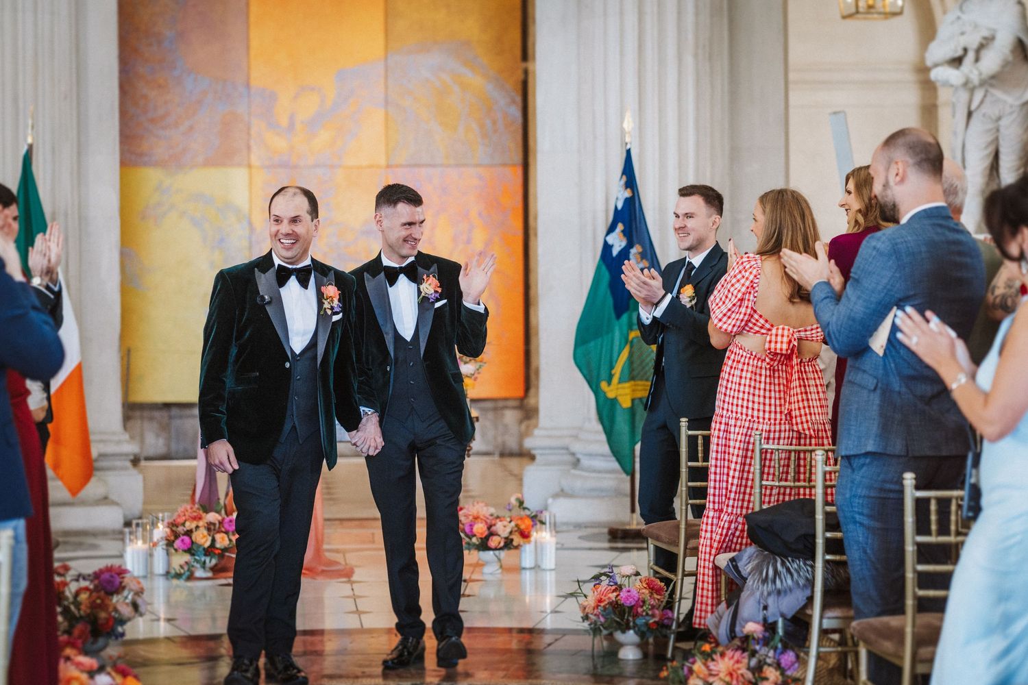 Wedding party celebrates with joyful dance moves during reception in an elegant ballroom with ornate decor.