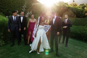 Wedding party walking together on a lush green lawn during golden hour sunset.