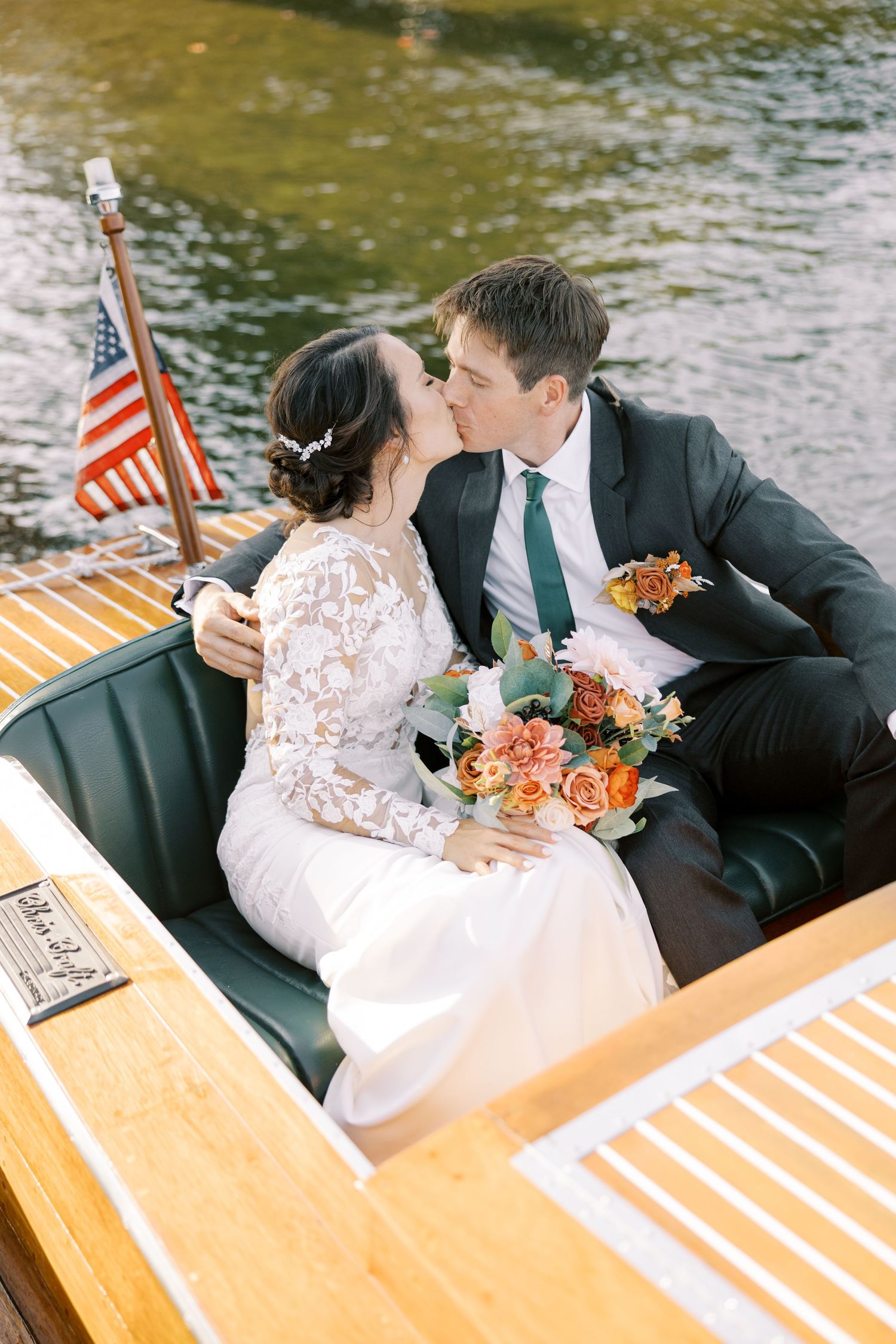 Romantic couple shares tender moments on a Chris-Craft on Lake Placid with American flag and orange floral bouquet.