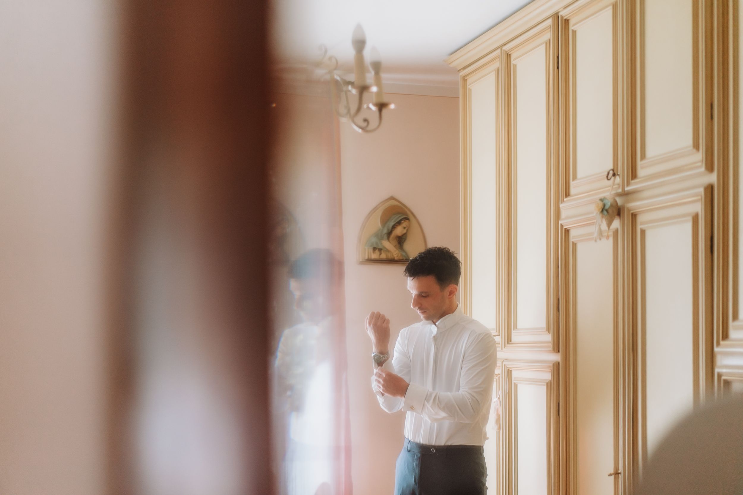 A luxurious hotel hallway with ornate gold trim moldings, cream walls, and elegant sconce lighting fixtures.