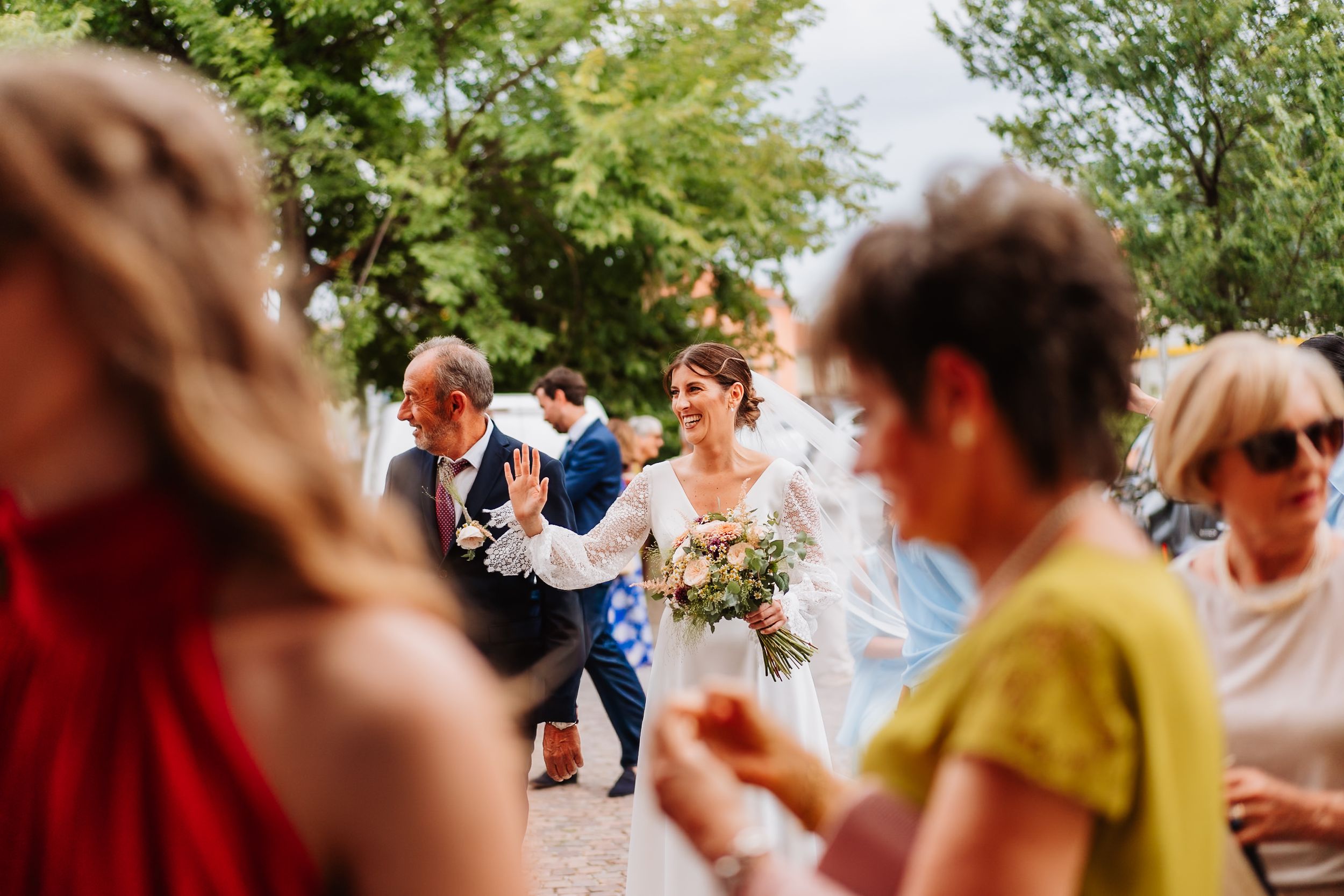 Wedding guests dance and celebrate on an outdoor dance floor during a sunny summer celebration.